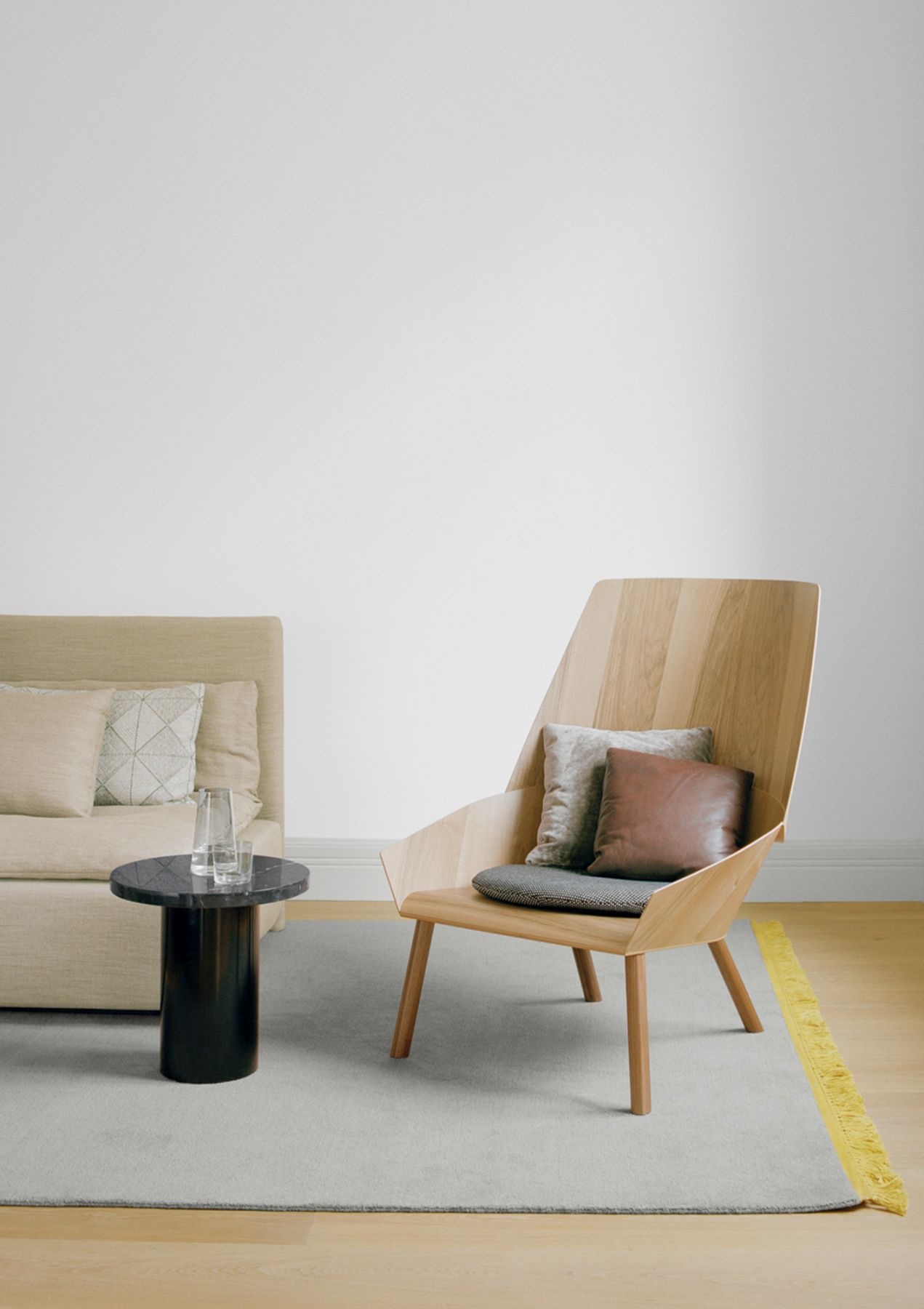 Enoki CT09 Beistelltisch e15 aus Marmor neben Sessel und Sofa im modernen Wohnzimmer.