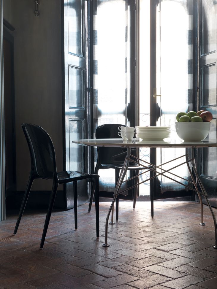 Glossy Kartell Tisch mit runder, marmorierter Steinzeugplatte und schwarzen Stühlen in einem Esszimmer.