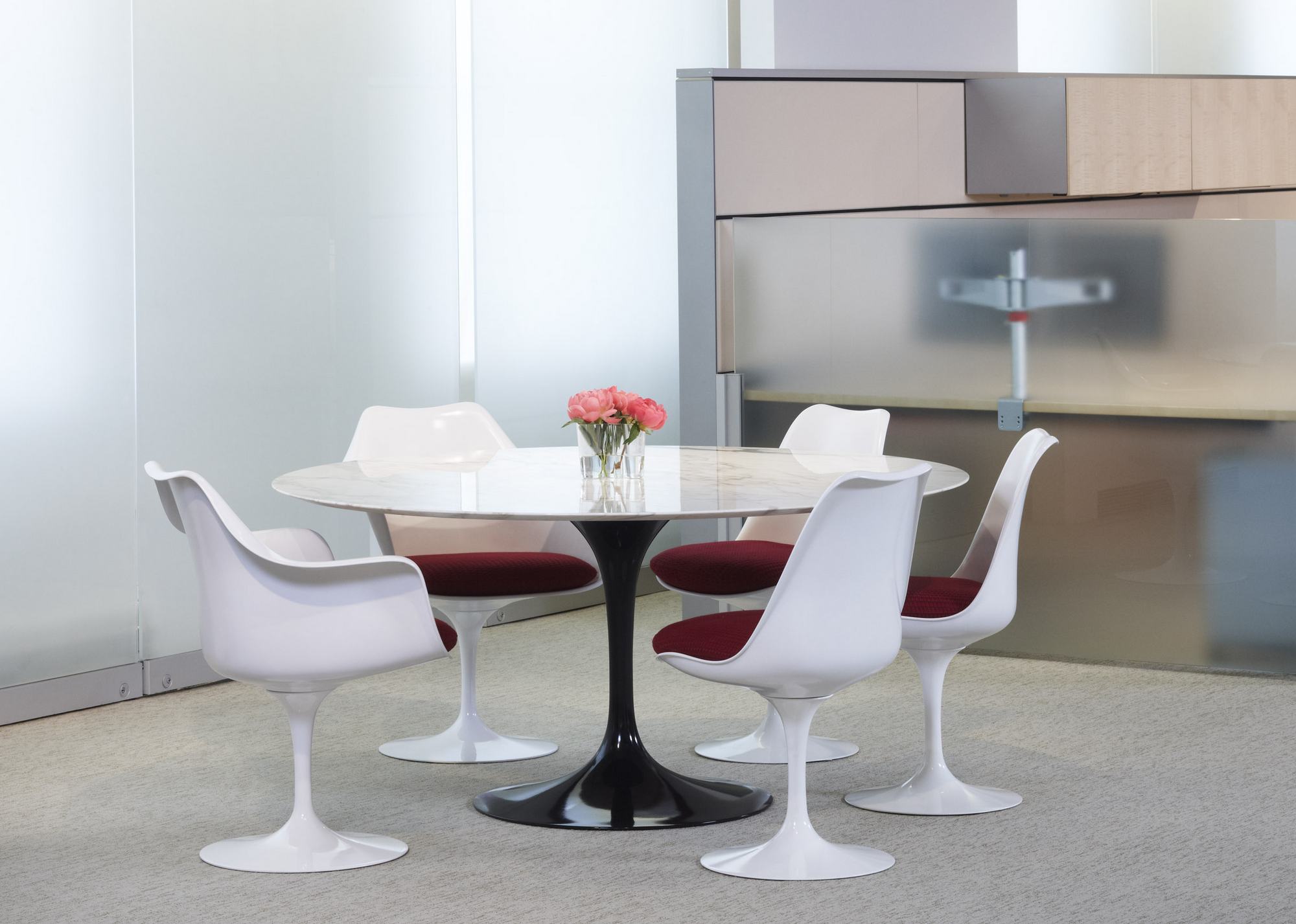 Esstisch mit Marmorplatte und vier weißen Tulip Armchair Drehstühlen von Knoll International mit roten Sitzkissen.
