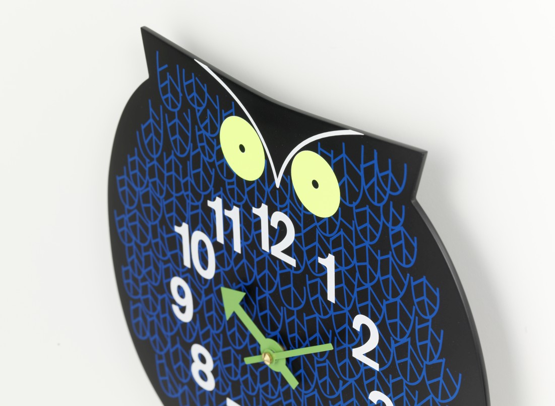Nahaufnahme der Omar the Owl Wanduhr von Vitra, Eule mit blauen Mustern und grünen Zeigern.