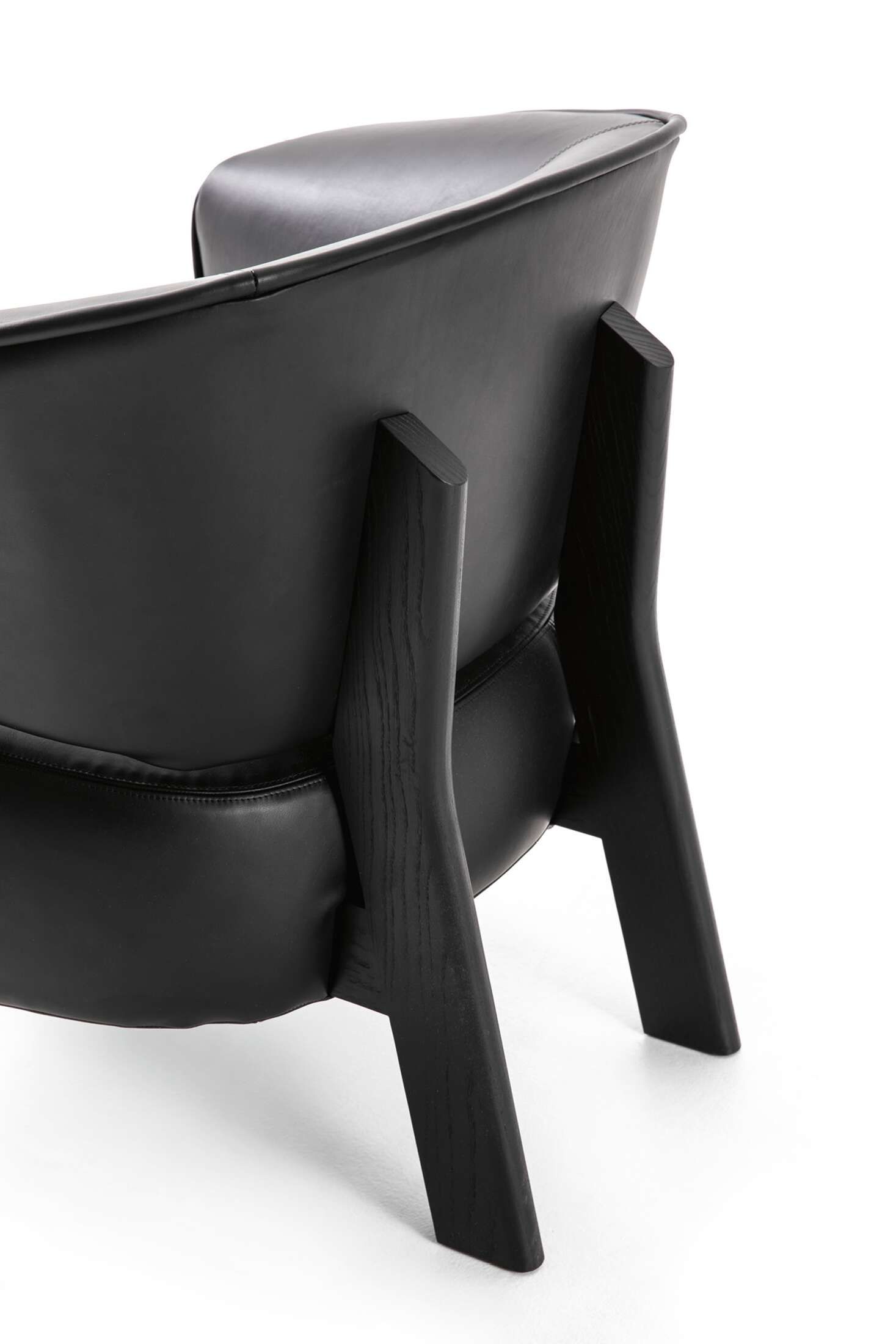 Detailaufnahme der Rückseite des schwarzen Cassina Back-Wing Sessels mit Holzbeinen auf weißem Hintergrund.