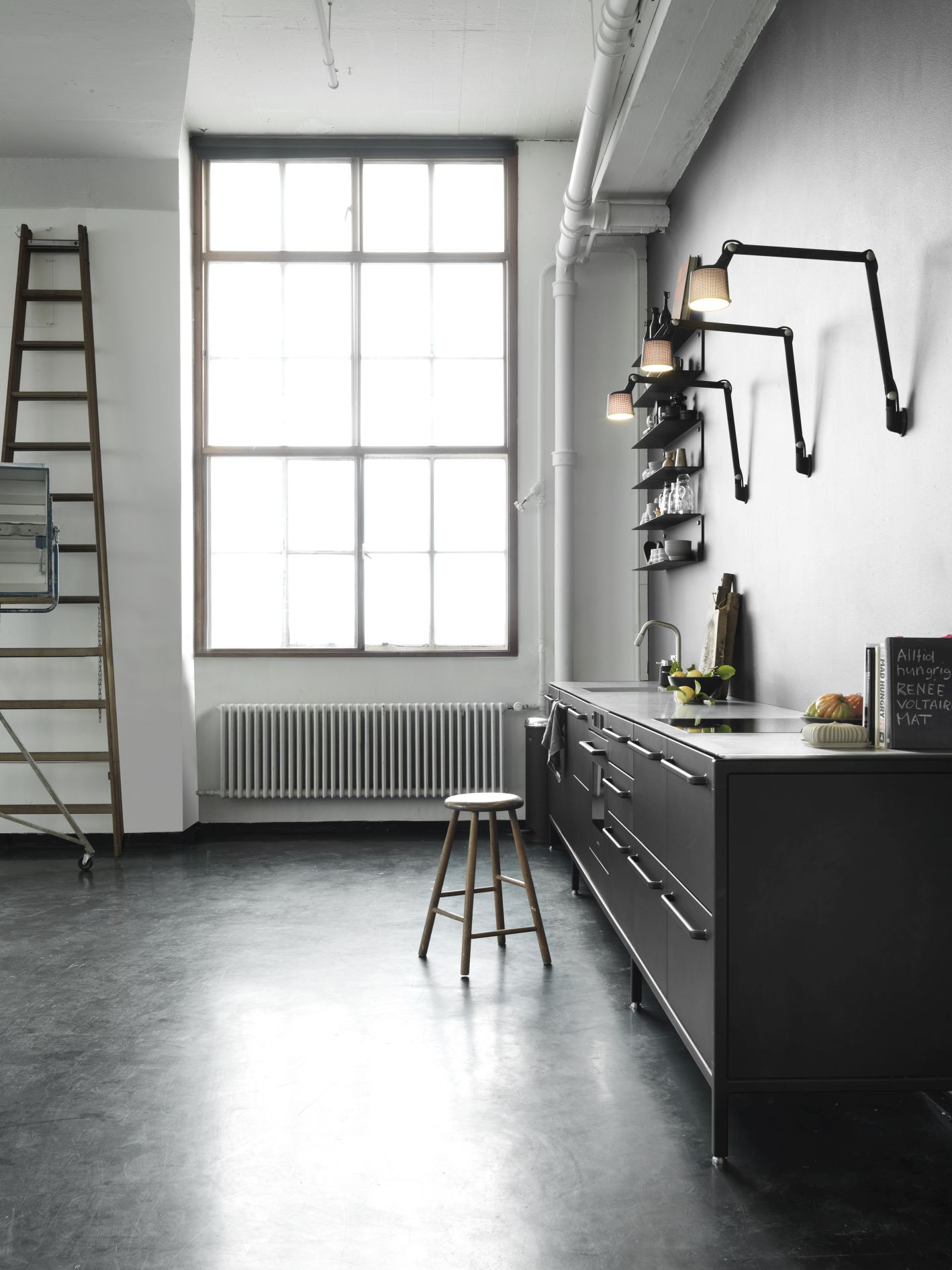 Moderne Küche mit Vipp Wandlampen, schwarzen Küchenschränken, Holzregal, Leiter und großem Fenster für stilvolle Innenarchitektur.