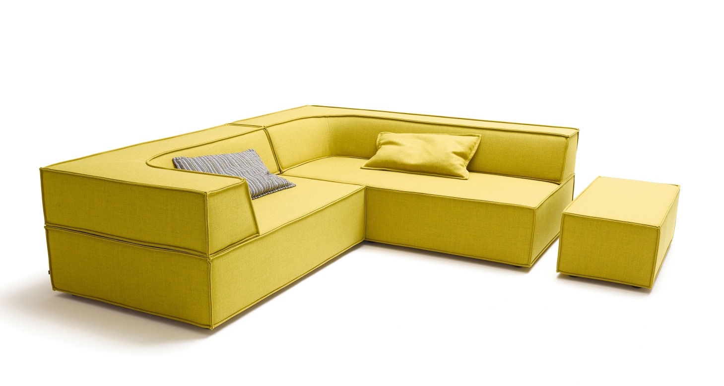 Gelbes Cor Trio Sofa mit Sitzelementen, zwei Kissen und einem Hocker auf weißem Hintergrund.
