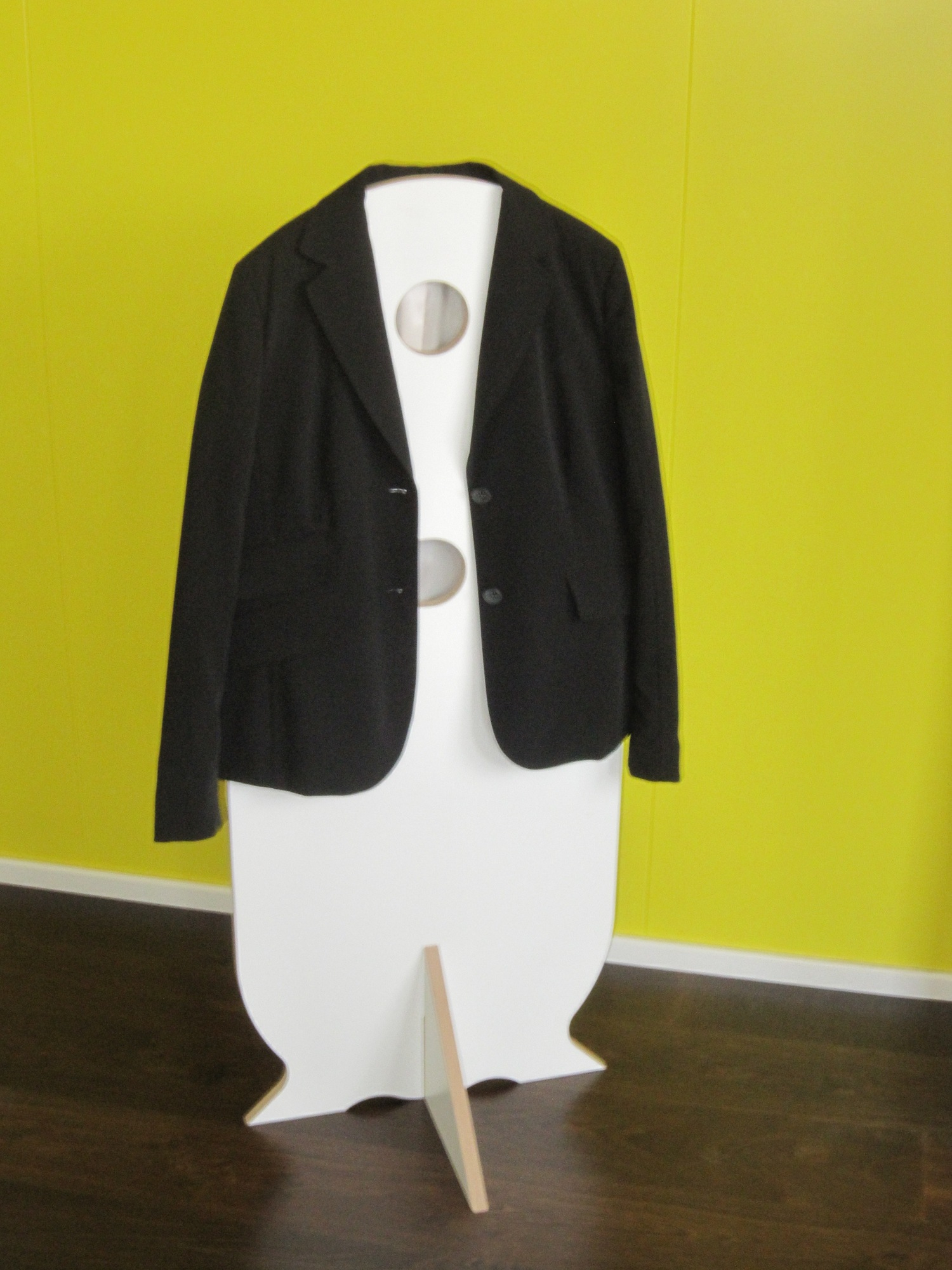 Dienerle Tojo: Schwarzer Blazer hängt auf einem weißen, modernen Kleiderdiener mit Löchern.