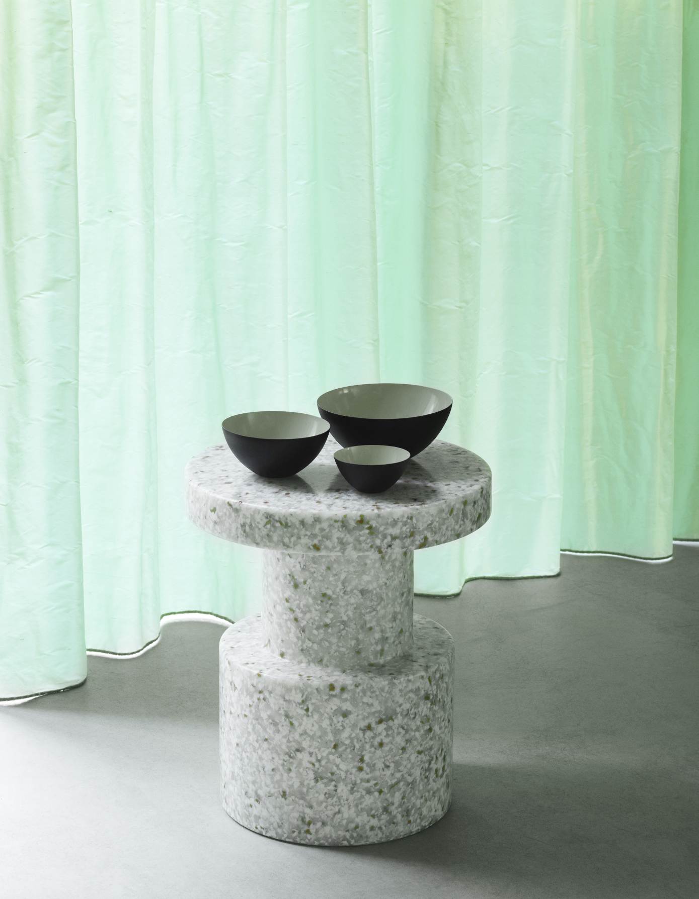 Normann Copenhagen Bit Stool Hocker in Weiß mit Schalen vor mintgrünem Vorhang.
