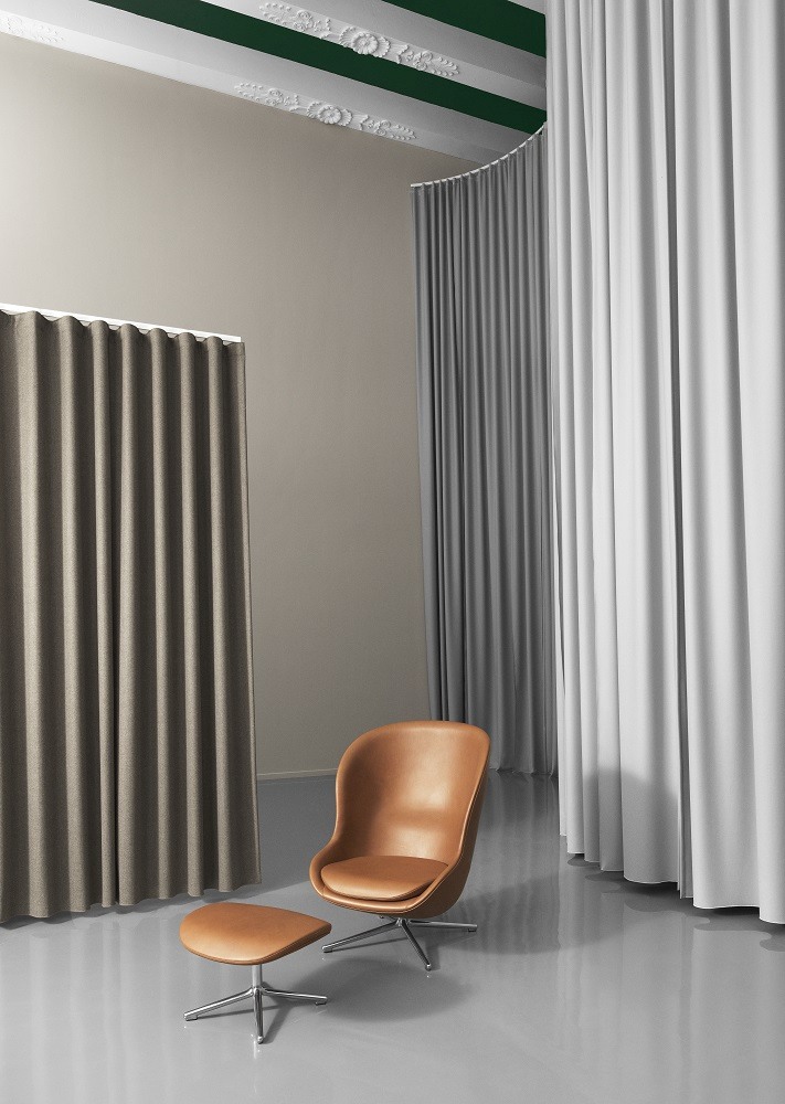 Brauner Hyg Lounge Chair mit Hocker von Normann Copenhagen vor Vorhängen. Sessel mit Drehgestell.