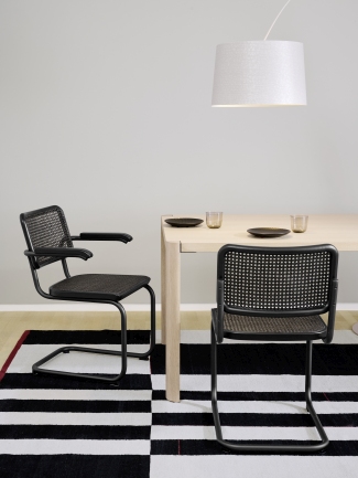 S 64 V Thonet Freischwinger Stühle mit Stahlrohrgestell und Wiener Geflecht an Esstisch auf Teppich.