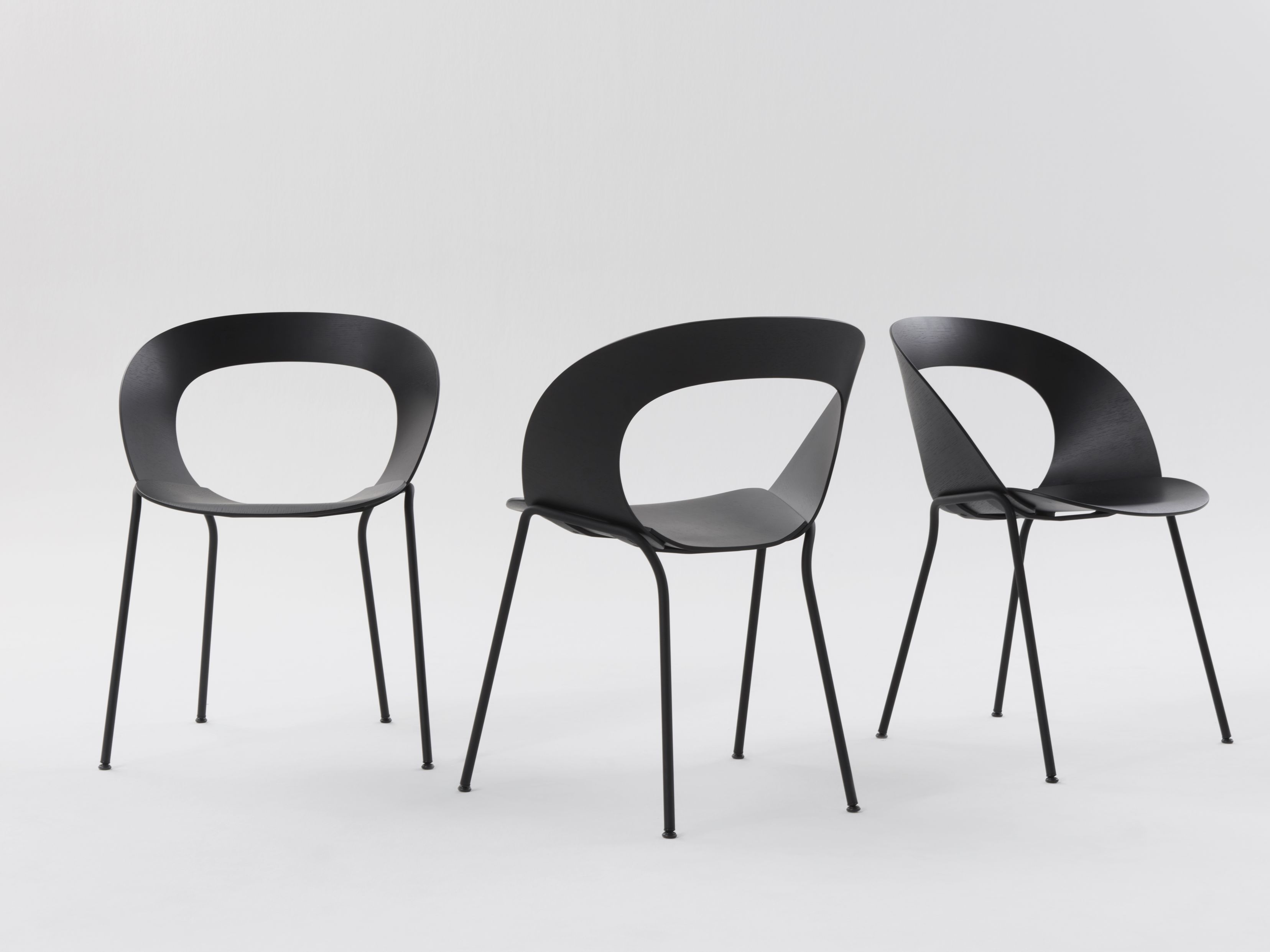 Drei schwarze Brunner Mudra Stühle mit minimalistischem Design und Stahlbeinen auf weißem Hintergrund.