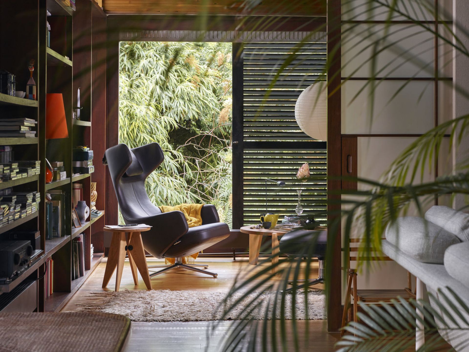 Schwarzer Ledersessel mit hoher Rückenlehne im Wohnzimmer mit Bücherregal und Holztischen, gemütliche Leseecke.