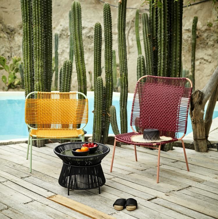 Gelbe und rote Rattansessel mit Beistelltisch im Garten, Outdoor Möbel für Terrasse und Balkon.