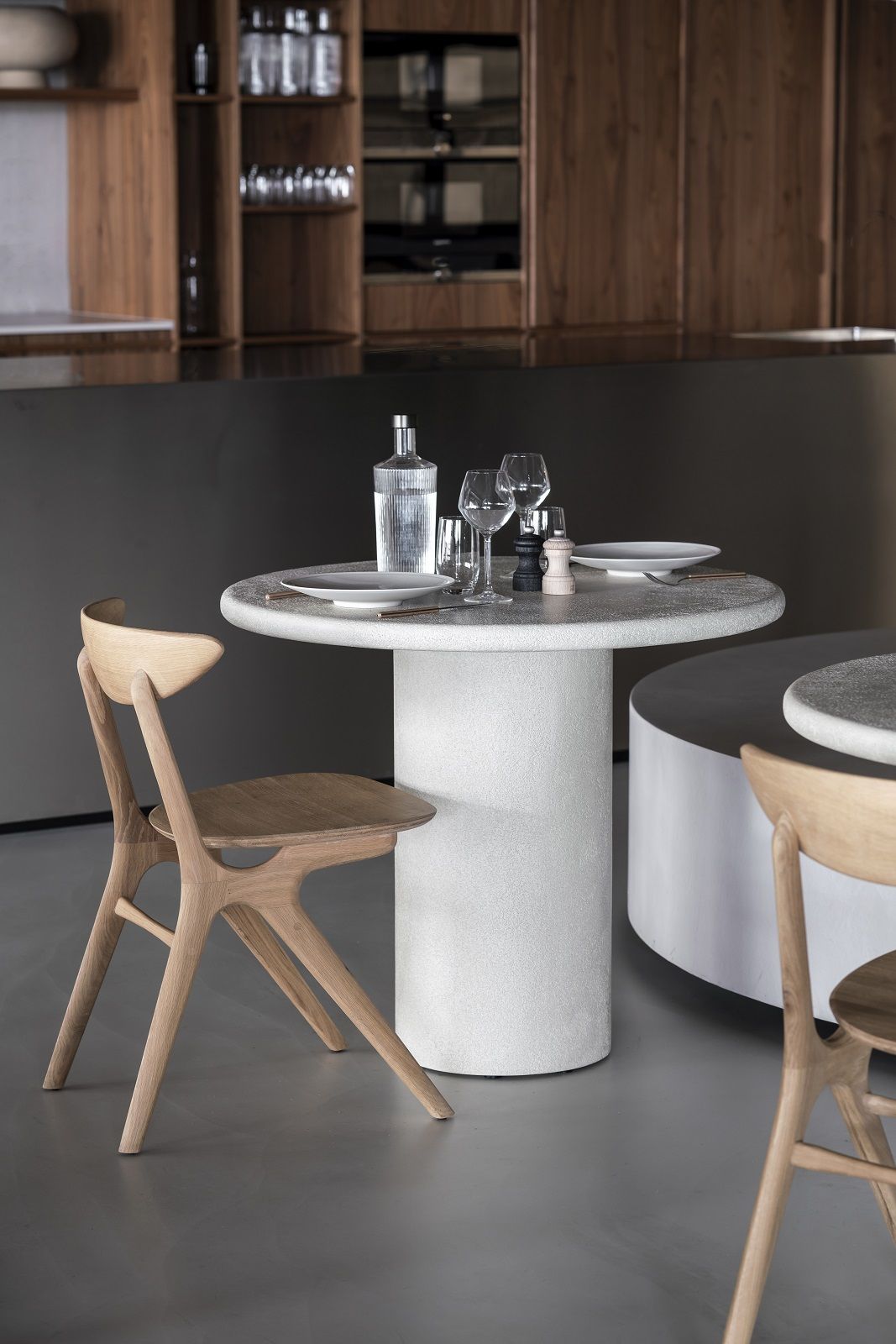 Elements Dining Table Esstisch von Ethnicraft, runder Esstisch aus hellem Stein mit Holzstühlen.