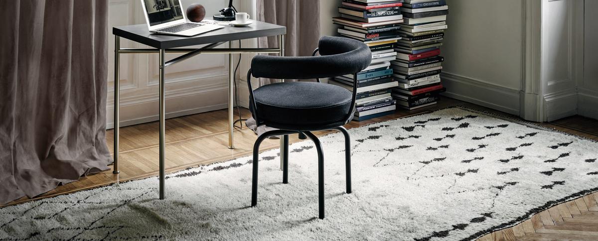 Schwarzer Cassina Drehsessel mit Armlehne am Schreibtisch auf Teppich. Moderner Design Drehstuhl.