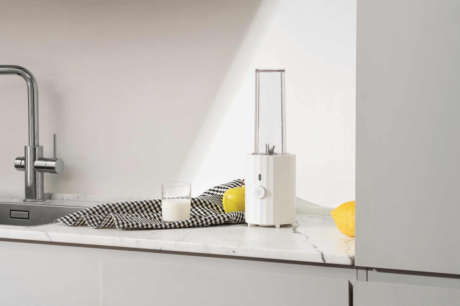 MDL17 Plissé Smoothie Maker von Alessi: Weißer Mini-Mixer mit Zitrone und Milch auf Marmor.