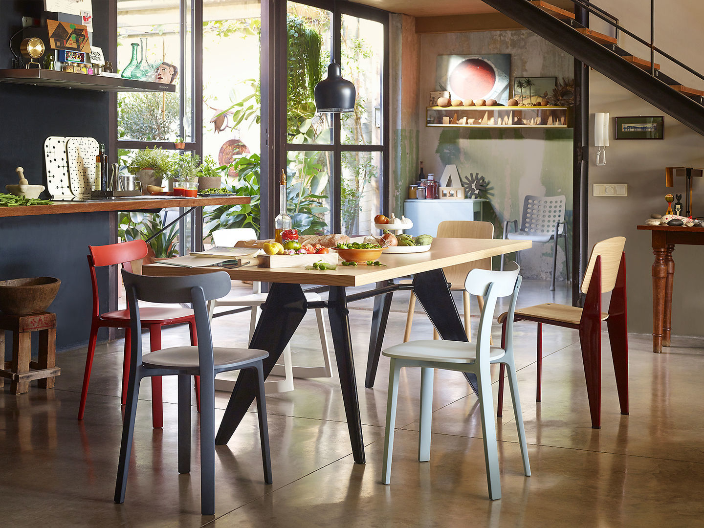 Esstisch mit verschiedenen Vitra Stühlen in Rot, Grau, Weiß und Hellblau im modernen Esszimmer.