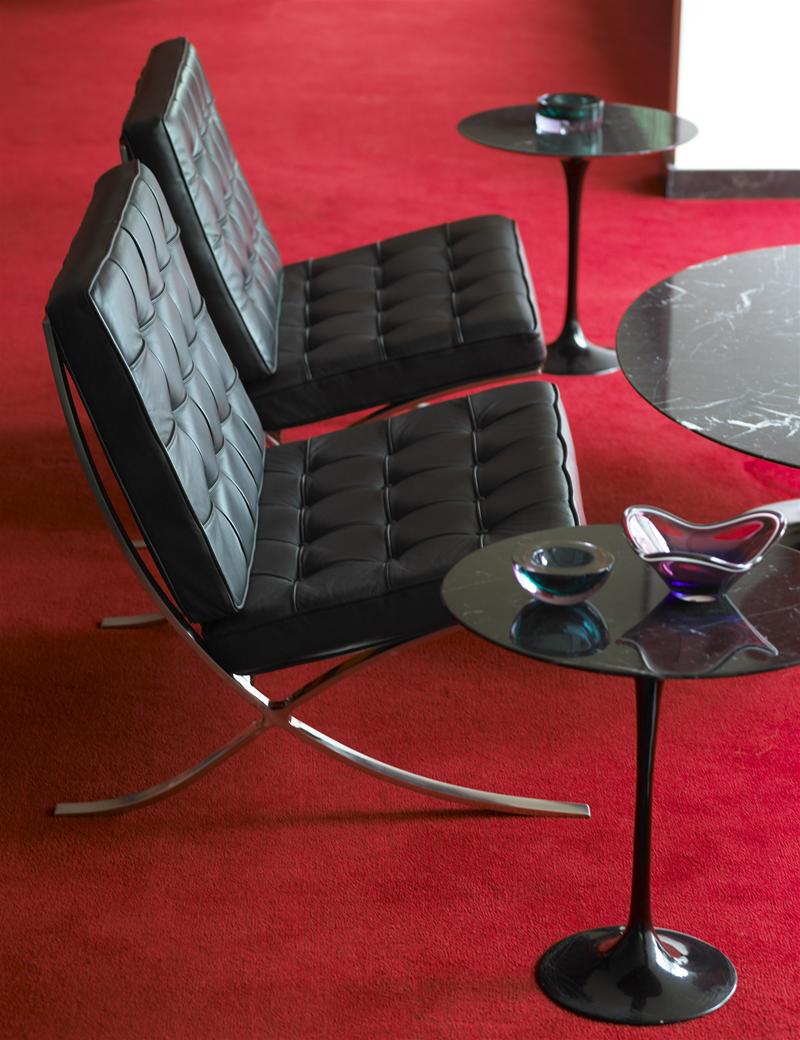 Zwei schwarze Barcelona Sessel von Knoll International mit Lederpolster und verchromtem Stahlgestell auf rotem Teppich.