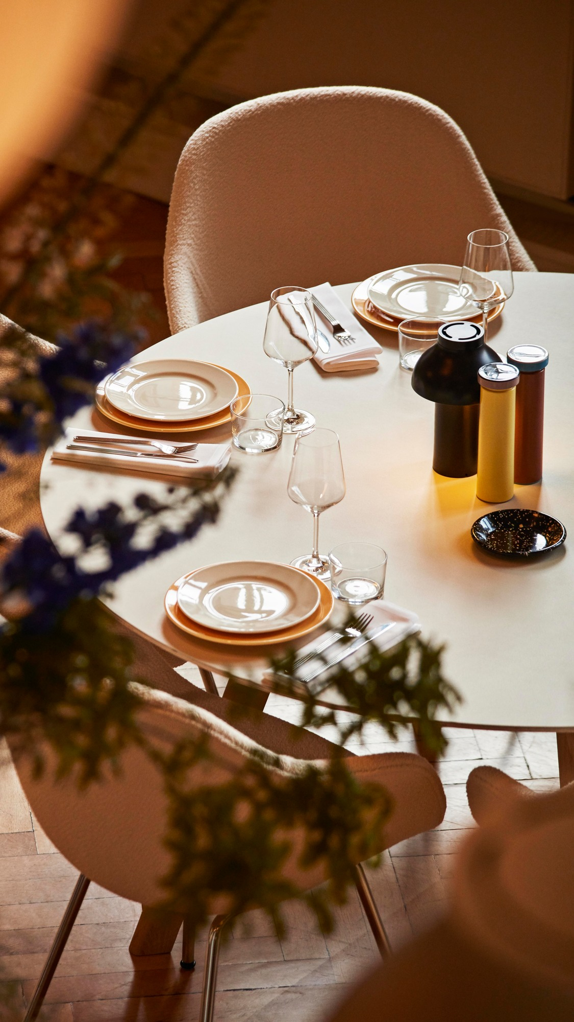 Esstisch mit Gedeck und zwei About a Chair AAC 127 Stühlen in Beige.