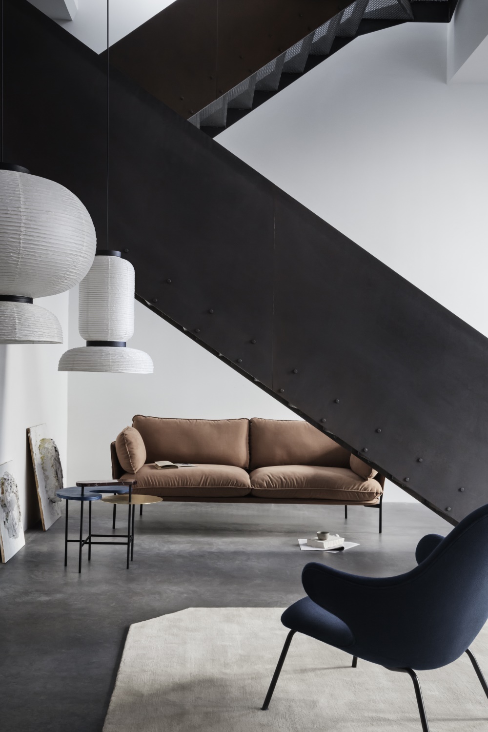 AndTradition Catch JH14 Lounge Sessel in blau vor modernem Wohnzimmer mit Sofa und Treppe.