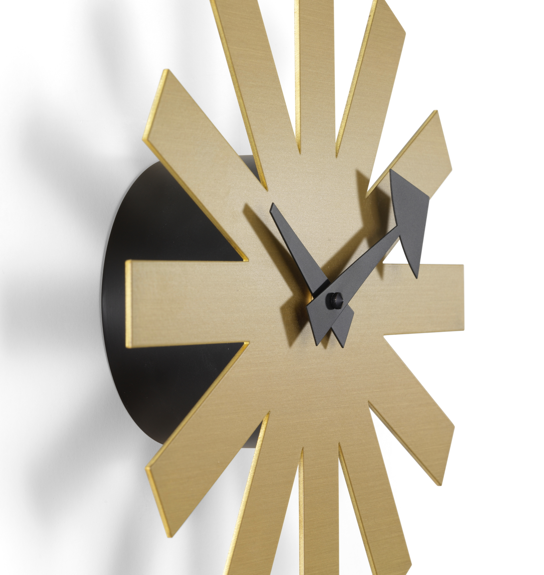 Nahaufnahme der Asterisk Wanduhr von Vitra in Messing mit schwarzen Zeigern.
