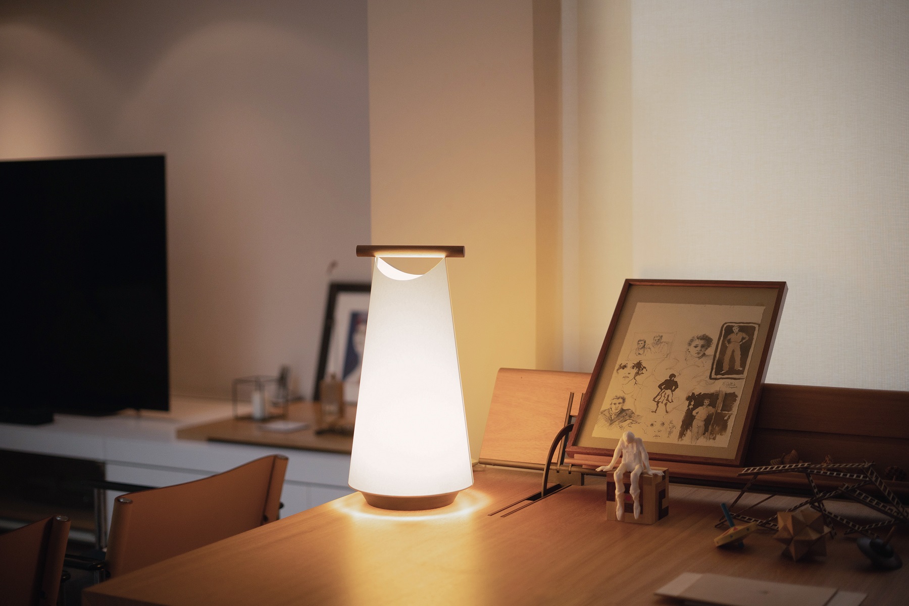 Catay Tischleuchte von Nomon, moderne Akku-Tischlampe mit warmem Licht auf einem Schreibtisch.