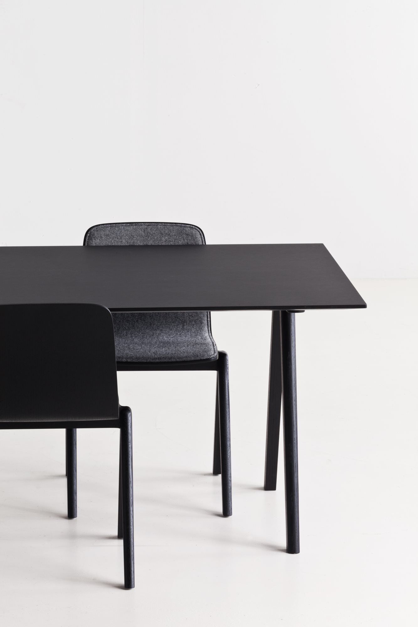 Schwarzer Copenhague Table CPH 10 Tisch von Hay mit zwei Stühlen vor weißem Hintergrund.