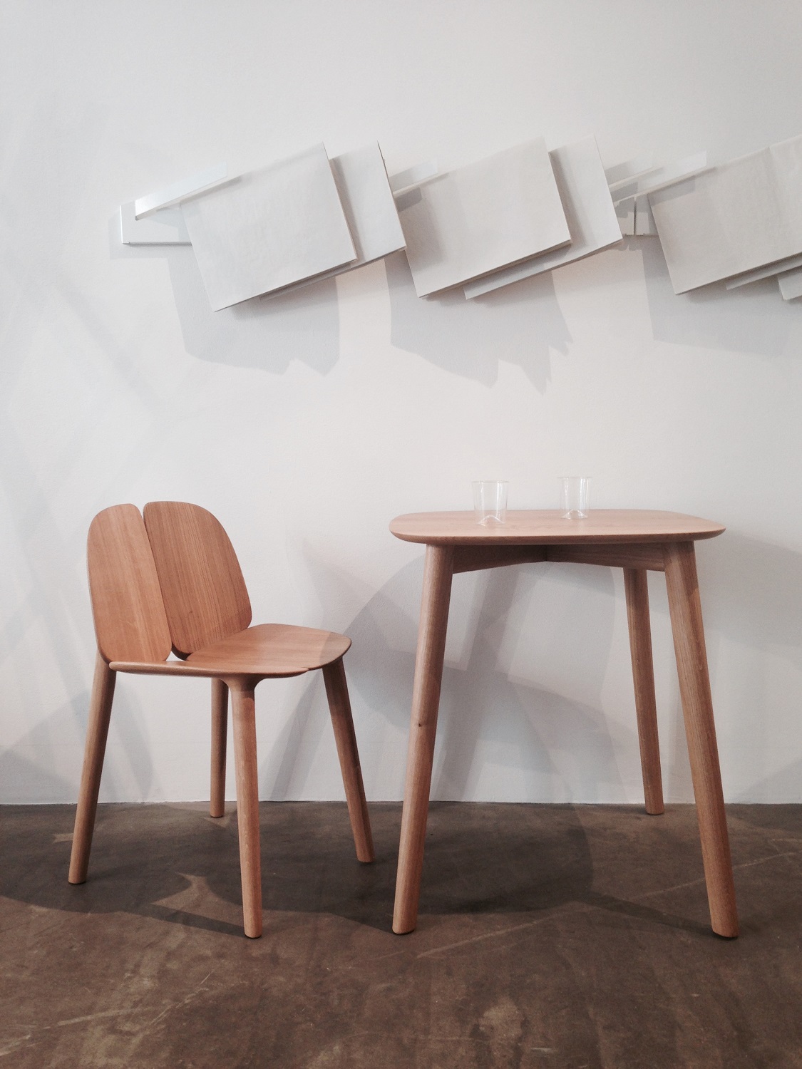 Heller Holztisch mit Stuhl und zwei Gläsern, minimalistisches Design für Esszimmer oder Küche.