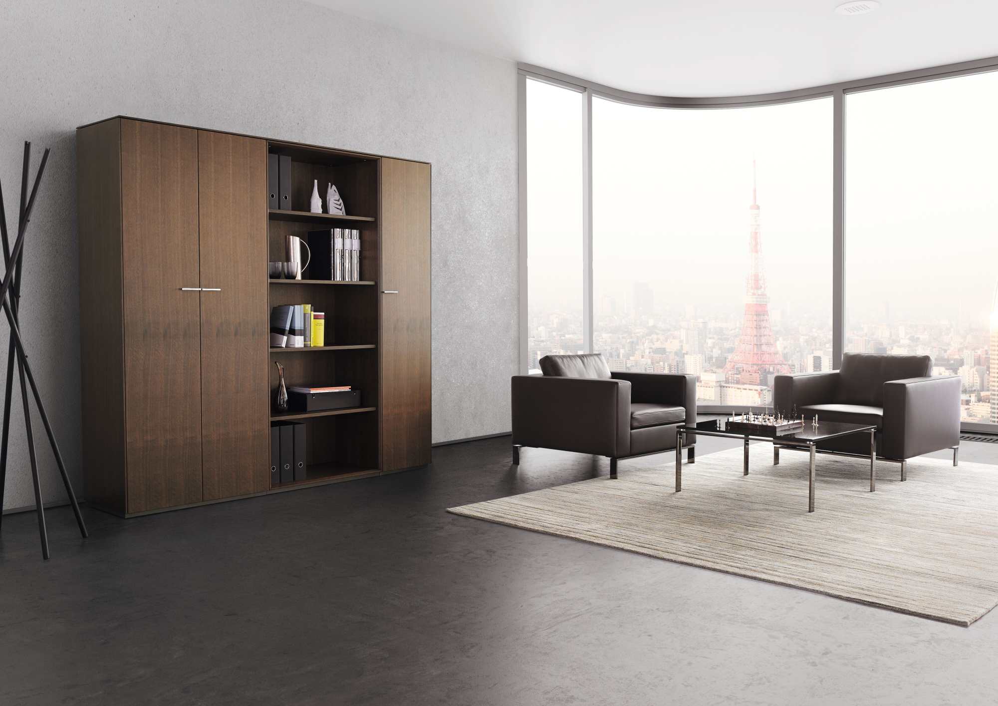 Moderner Walter Knoll Sessel 503 Foster in braunem Leder, mit Bücherschrank und Skyline im Hintergrund.