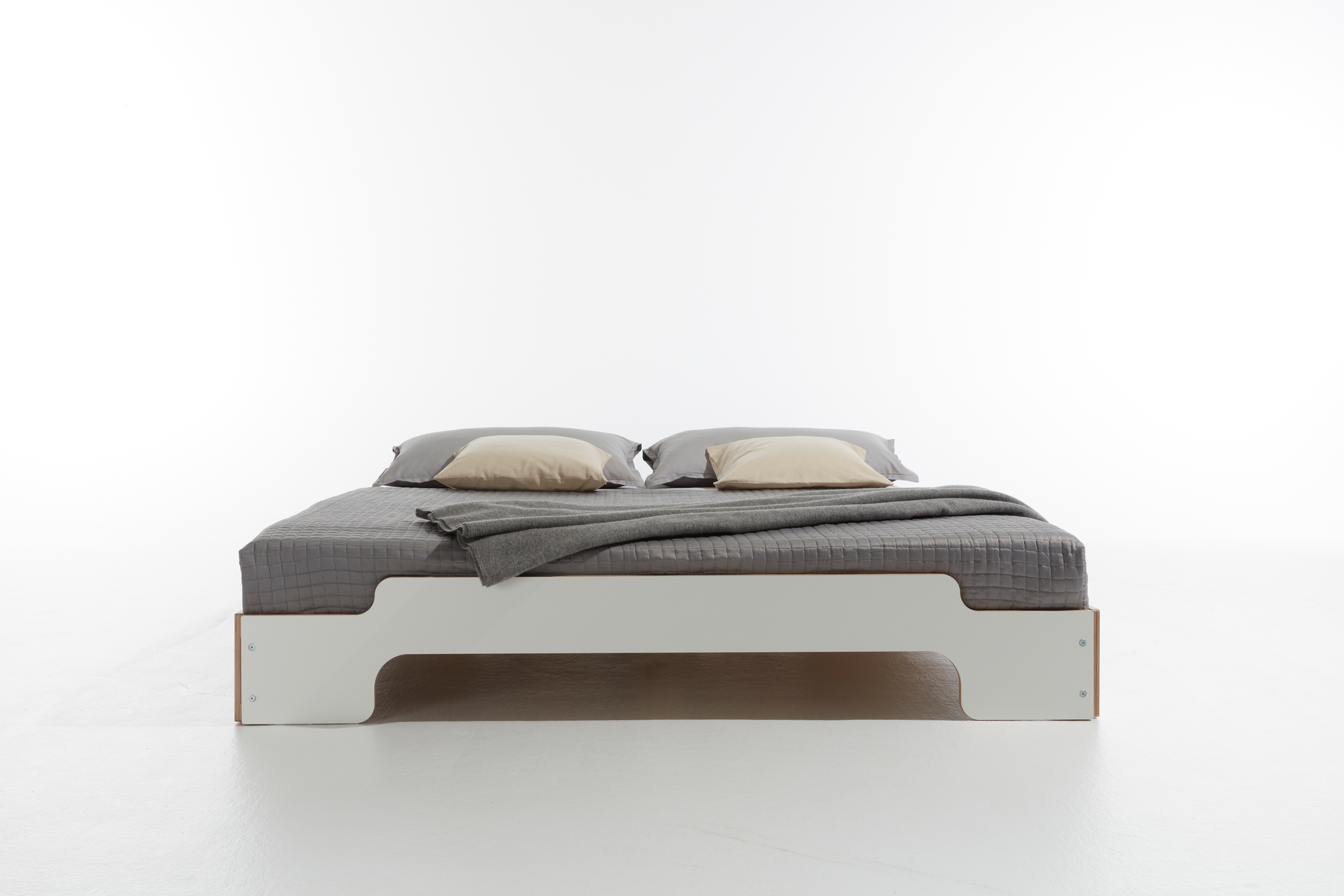 Weißes Stapelliege Bett von Müller Möbelwerkstätten mit grauer Bettwäsche und Kissen. Komfortable Schlafstätte.