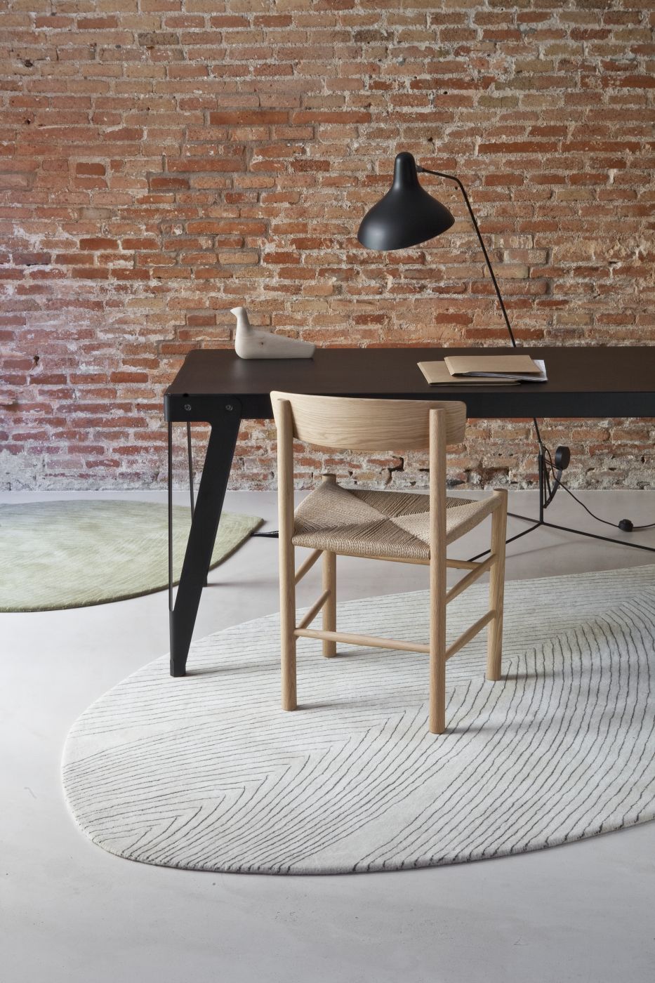 Nanimarquina Teppich Quill, 150x260 cm, in Weiß mit grafischem Muster unter einem Stuhl.
