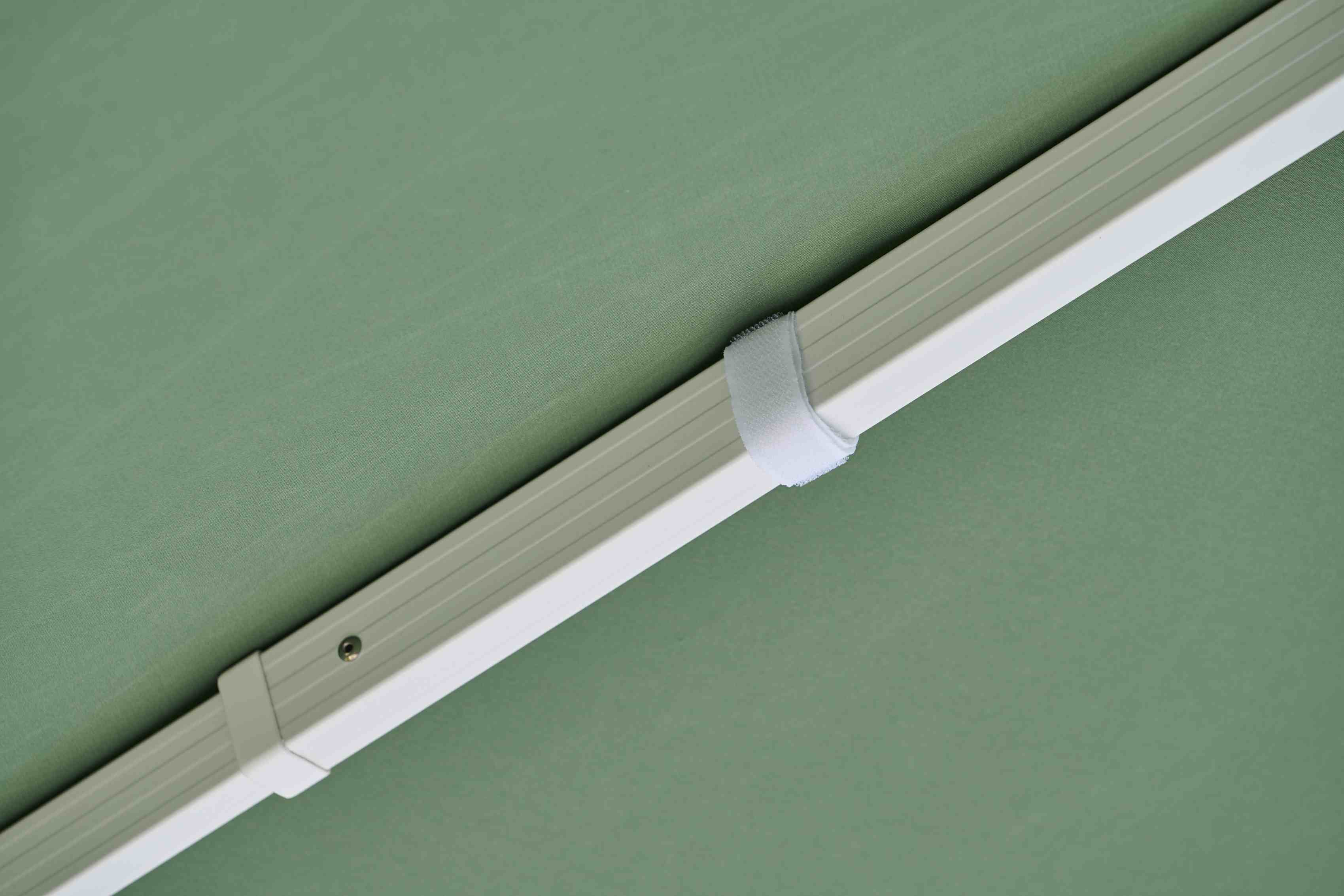 Detailaufnahme des Weishäupl Sonnenschirms in Grün, der weiße Rahmen und ein Klettband sind sichtbar.