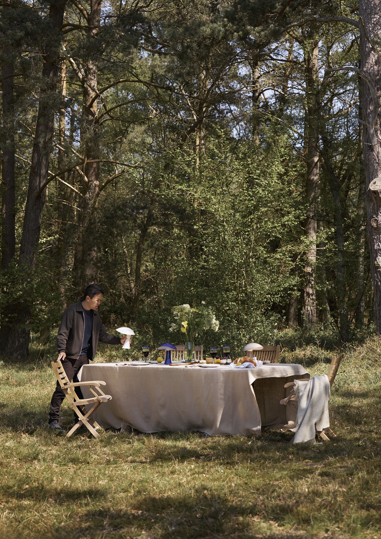 Rumee Akkuleuchte von Louis Poulsen auf gedecktem Tisch im Freien, stimmungsvolle Beleuchtung für Outdoor-Dinner.