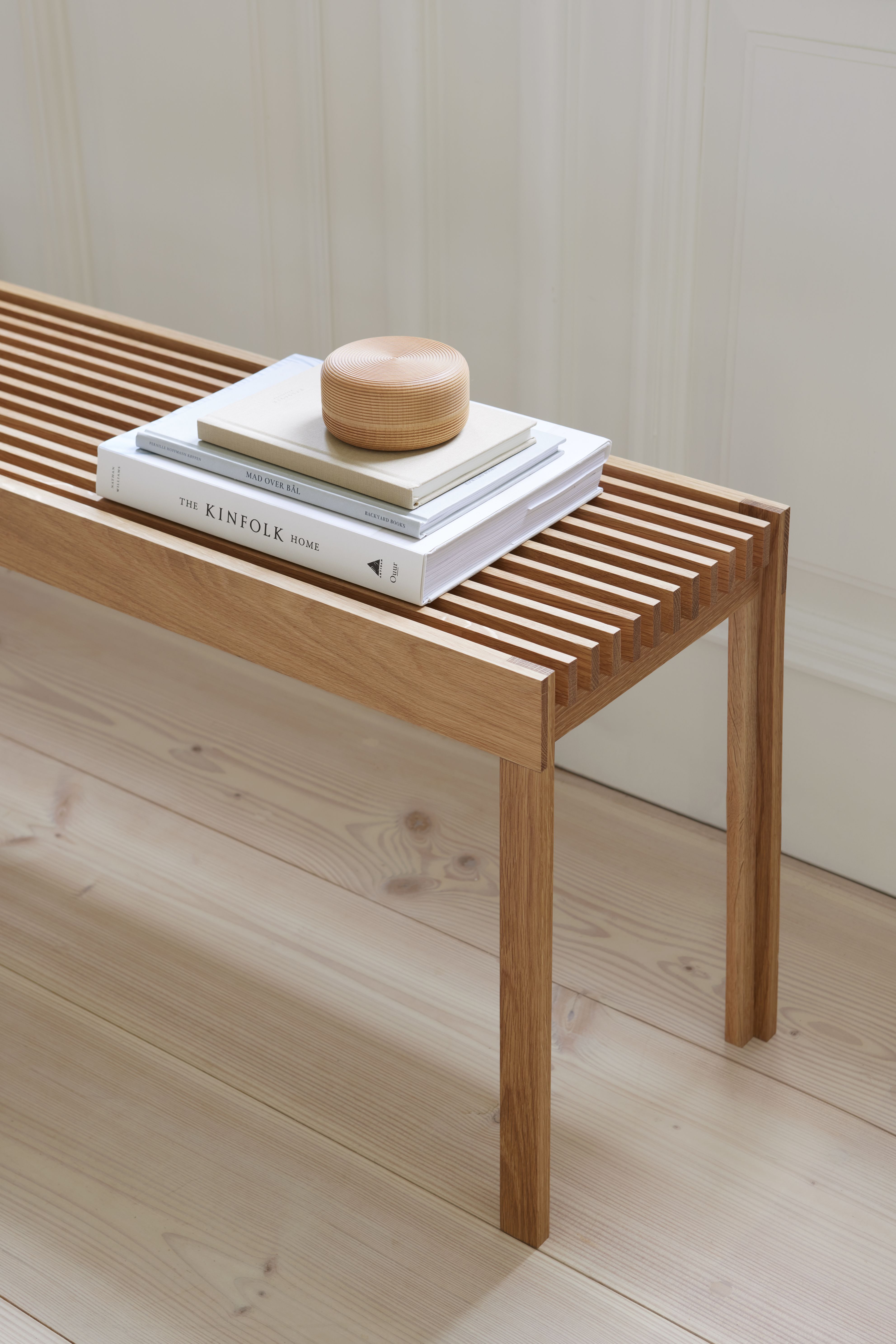 Leichte Eichenbank mit geölter Oberfläche, Bücher und Holzobjekt darauf, minimalistisches Design für Wohnzimmer und Flur.
