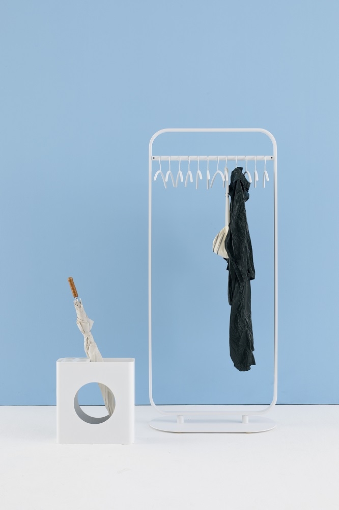 Weiße Focus Standgarderobe von Cascando mit Kleidung und Schirmständer vor hellblauem Hintergrund.