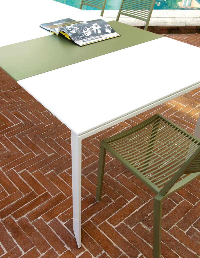 Grande Arche Outdoor Tisch von Fast, Gartentisch mit weißer und grüner Tischplatte, Stuhl im Hintergrund.