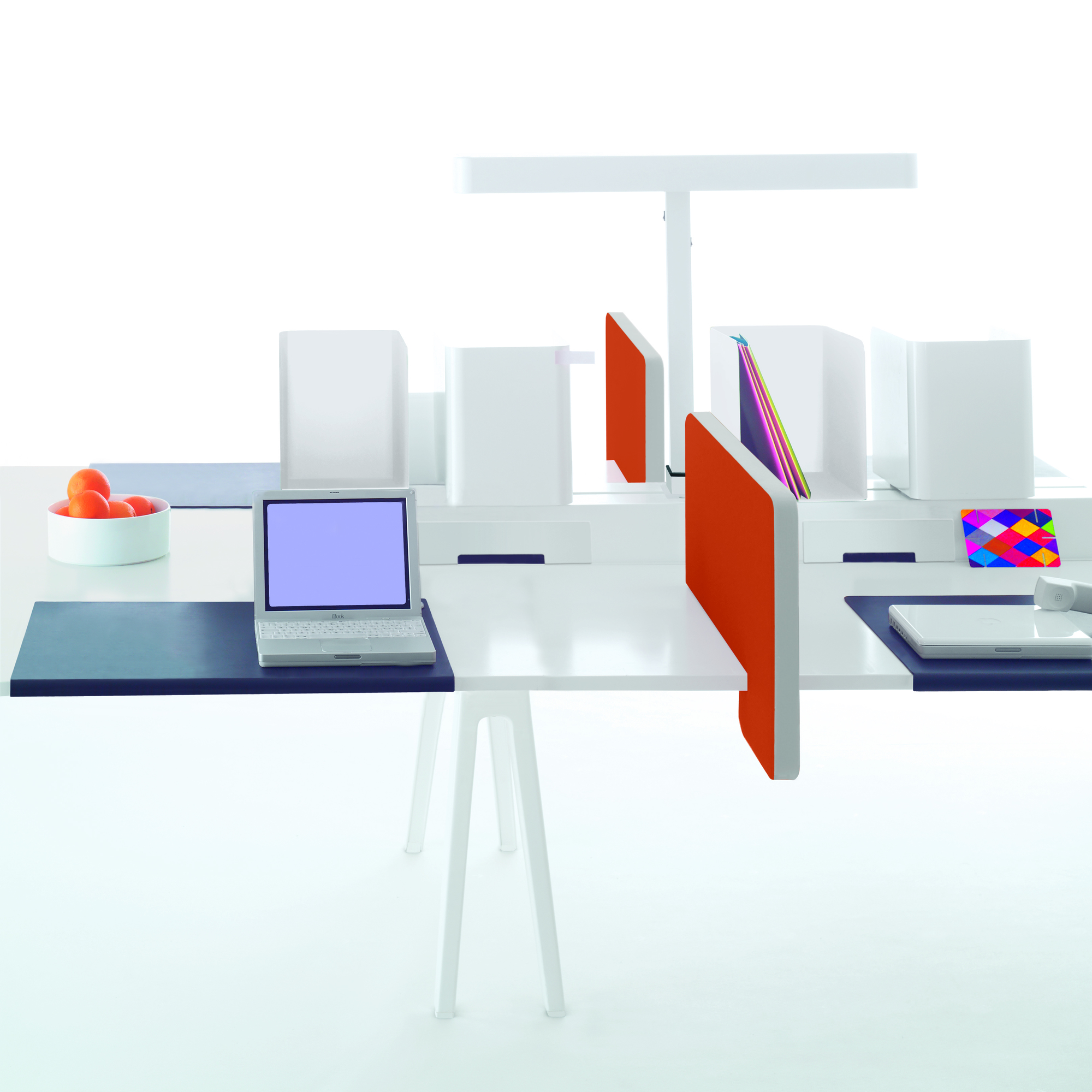Vitra Joyn Schreibtisch mit Laptop, Orangen, farbigen Trennwänden und Büromaterial für moderne Arbeitsplätze.