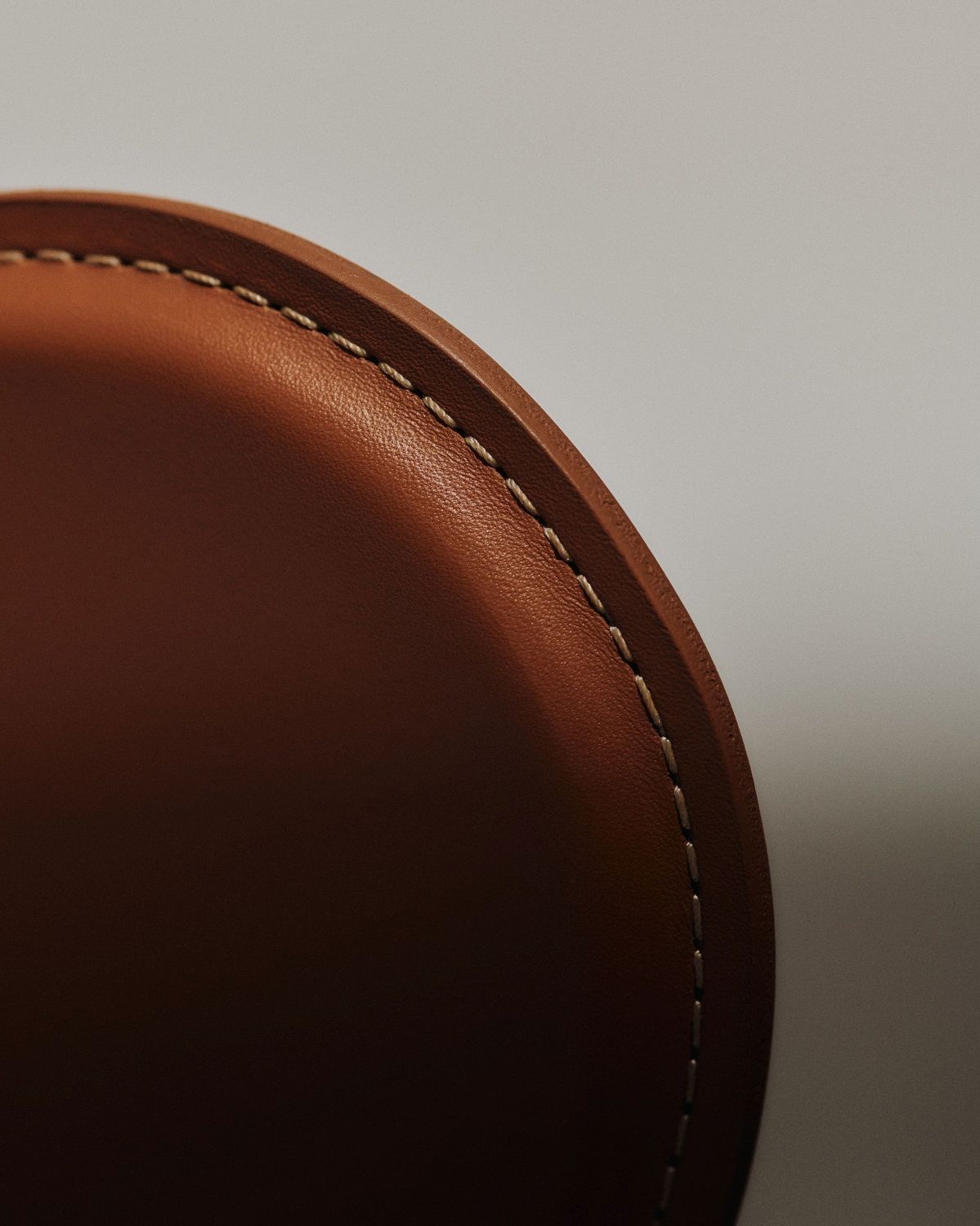 Detailaufnahme: Brauner Siebener Stuhl von Fritz Hansen mit feinen Ziernähten, Lederstuhl Nahaufnahme.