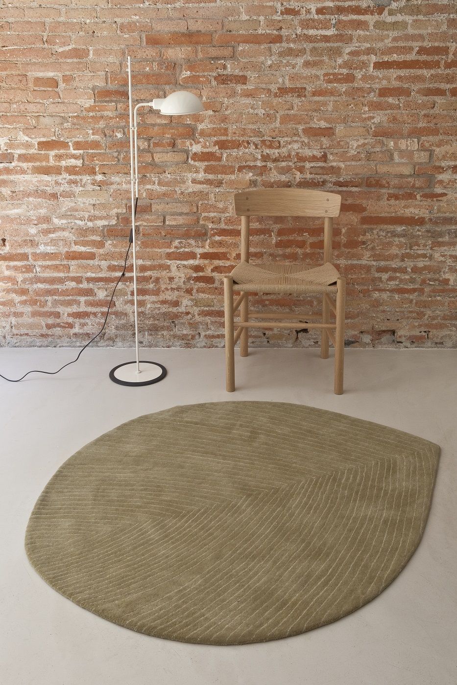 Nanimarquina Teppich Quill in Blattform, modernes Design mit Stuhl, Lampe und Ziegelwand.