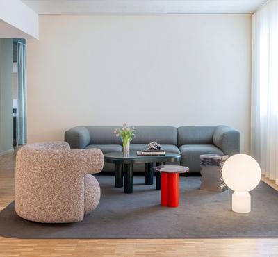 Wohnzimmer mit grauem Sofa, Sessel und Normann Copenhagen Dit Coffee Table Beistelltisch in Rot und Grau.