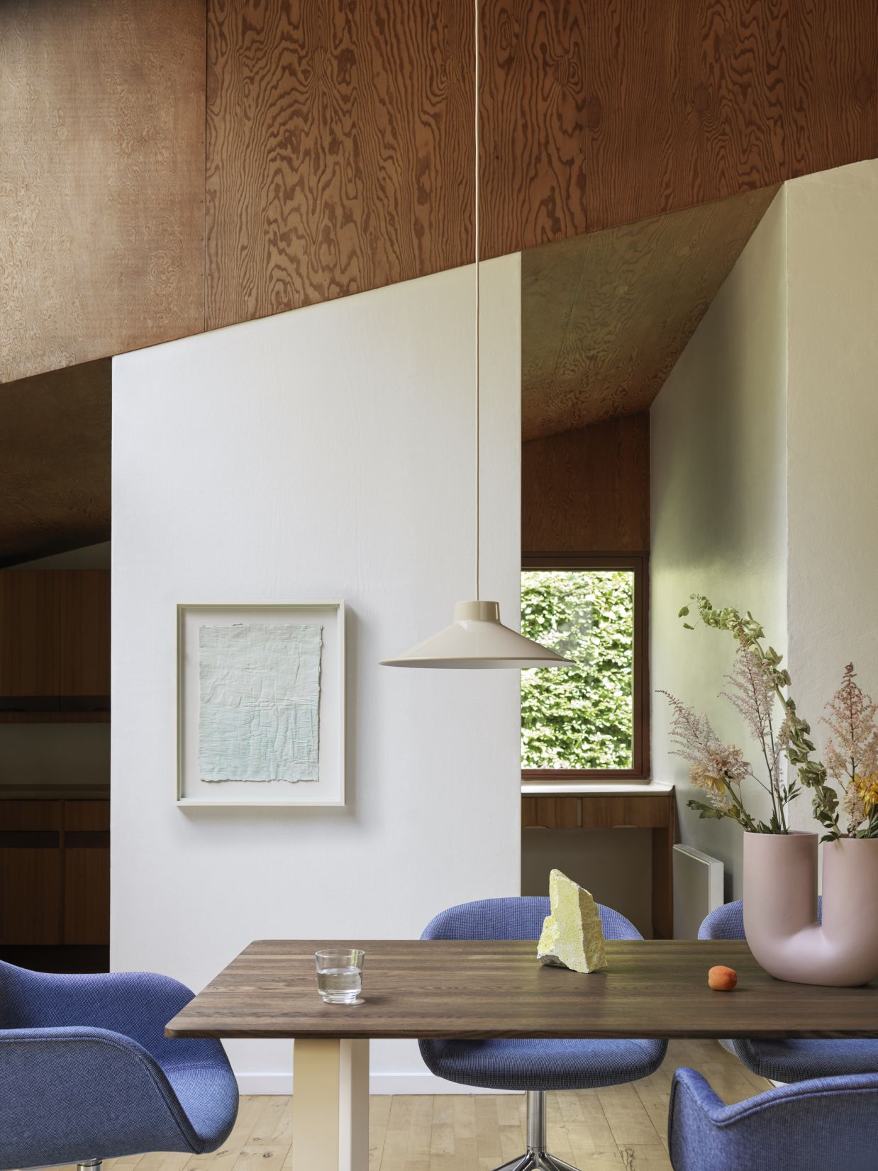 Beige Muuto Top Pendant Pendelleuchte über Esstisch mit blauen Stühlen und Dekoration in modernem Interieur.