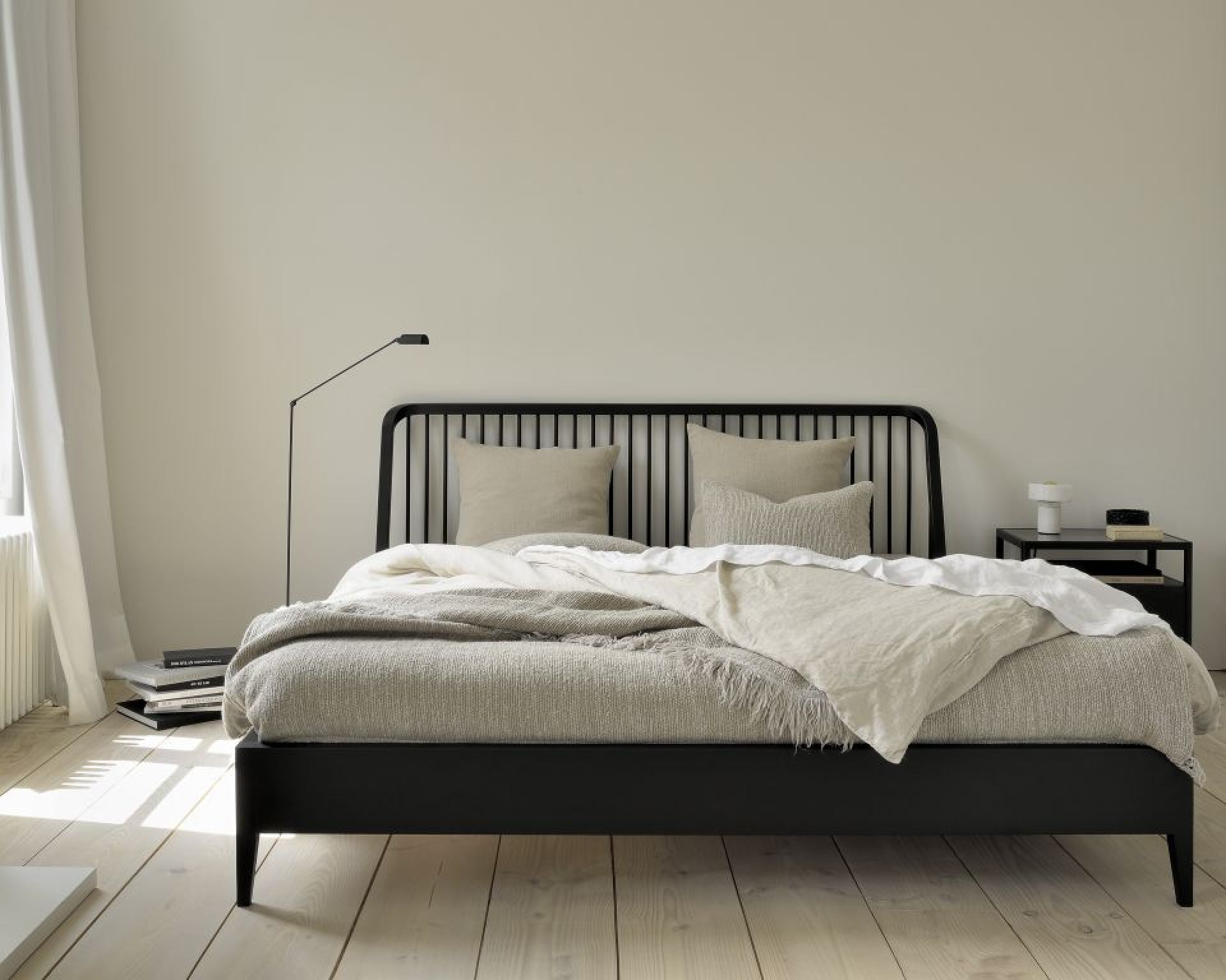 Schwarzes Bettgestell mit Lattenrost und beiger Bettwäsche, Kissen und Decke in einem hellen Schlafzimmer.