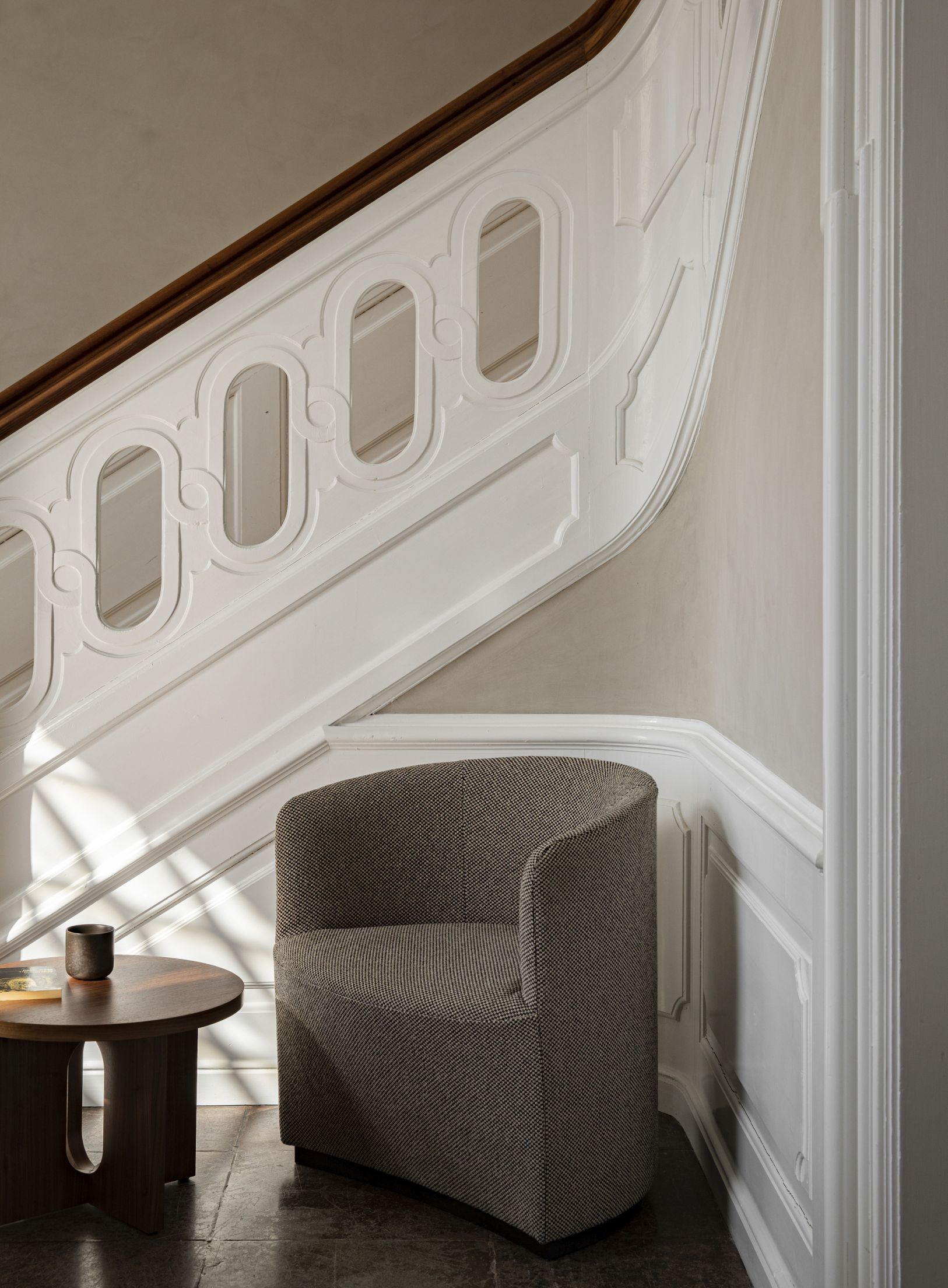 Androgyne Beistelltisch von Audo neben Sessel und Treppe, modernes skandinavisches Design für Wohnzimmer.