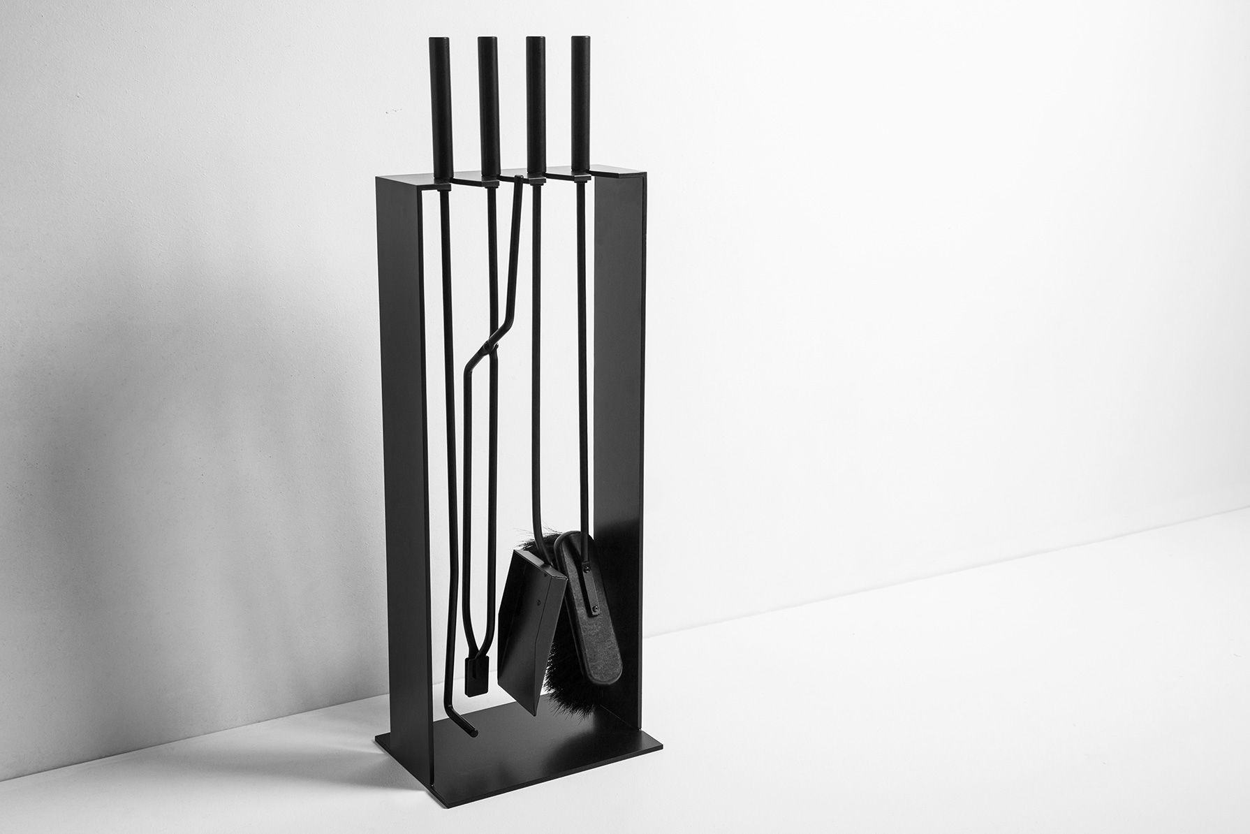 Schwarzes Conmoto Kaminbesteck Norma mit Schürhaken, Schaufel, Besen und Zange im minimalistischen Design.