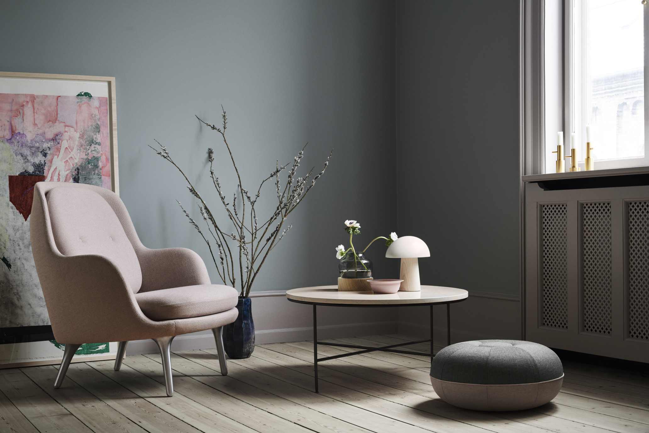Heller Fri Sessel von Fritz Hansen in stilvollem Wohnzimmer mit Beistelltisch und Hocker.
