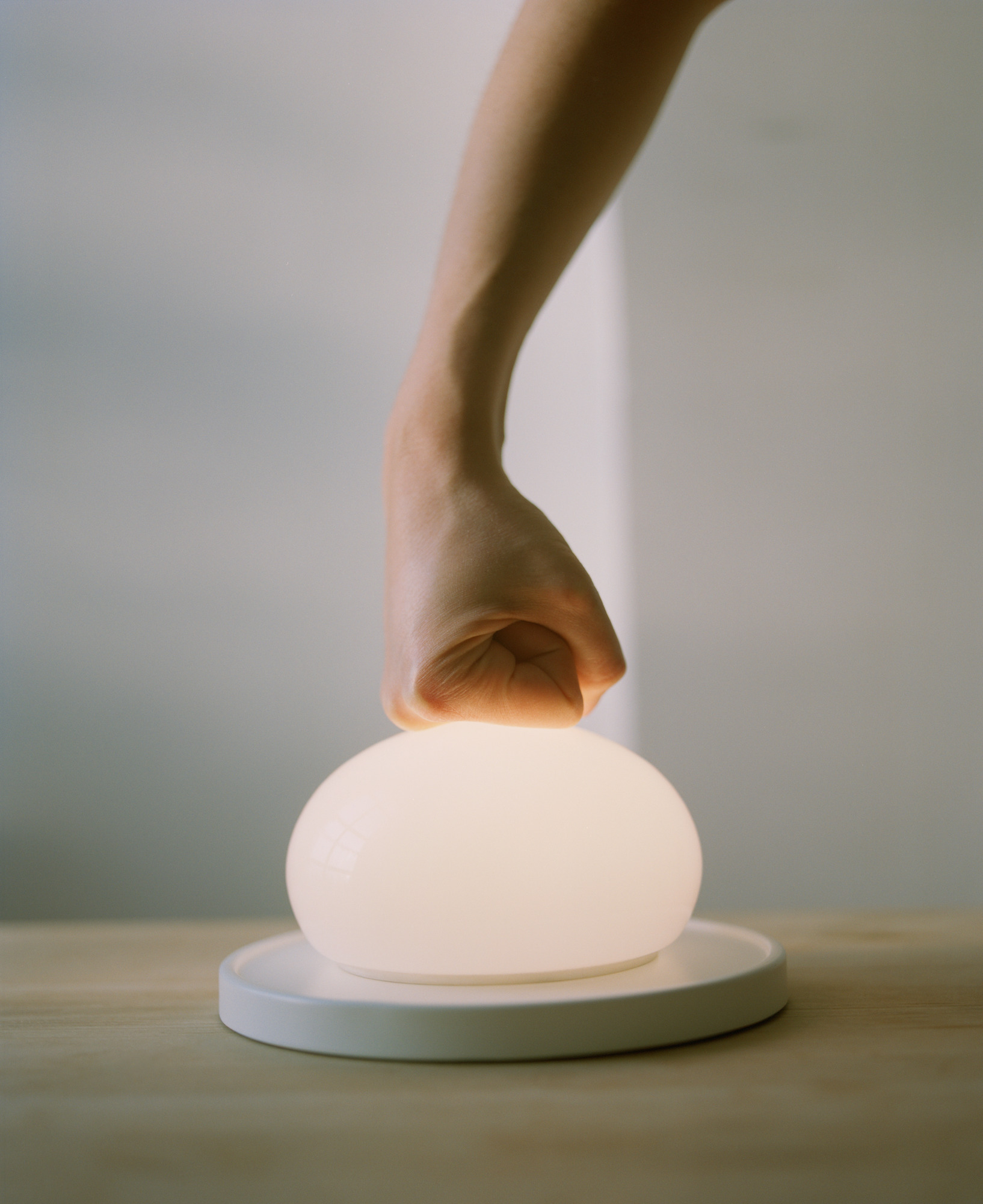 Hand schaltet Bolita LED Tischleuchte von Marset ein, modernes Design mit warmem Licht.