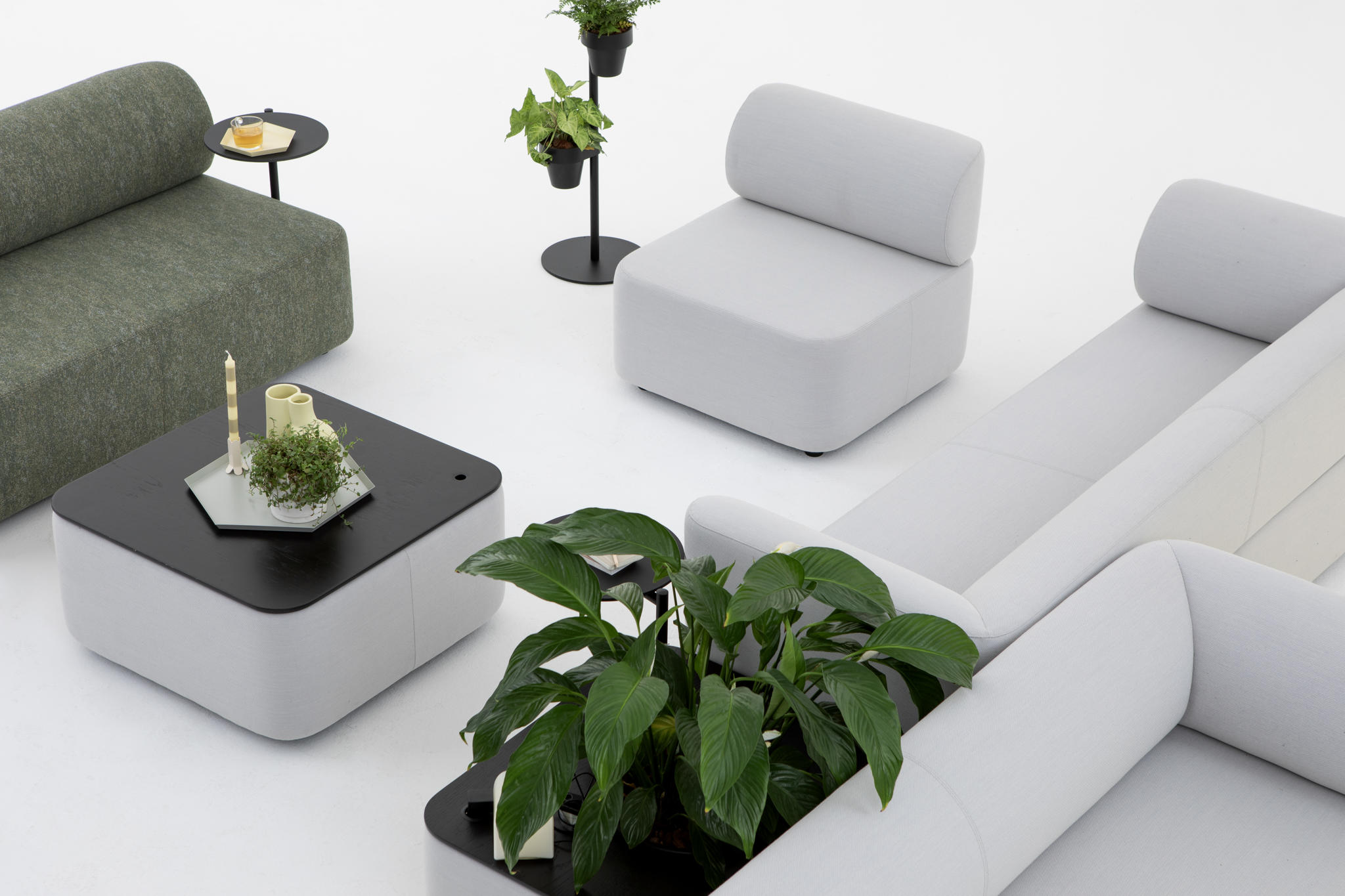 Mezza Sitzelemente und graues Cascando Sofa mit Rückenlehne in moderner Büroumgebung mit Pflanzen.
