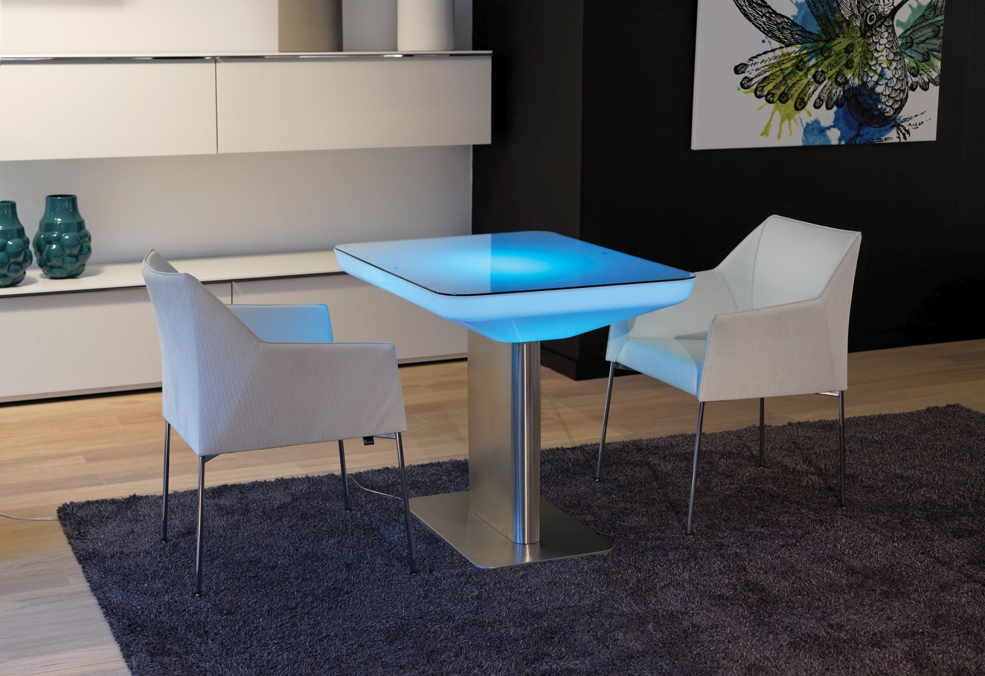 Studio 75 LED Tisch mit blauer Beleuchtung und zwei Stühlen auf einem Teppich.
