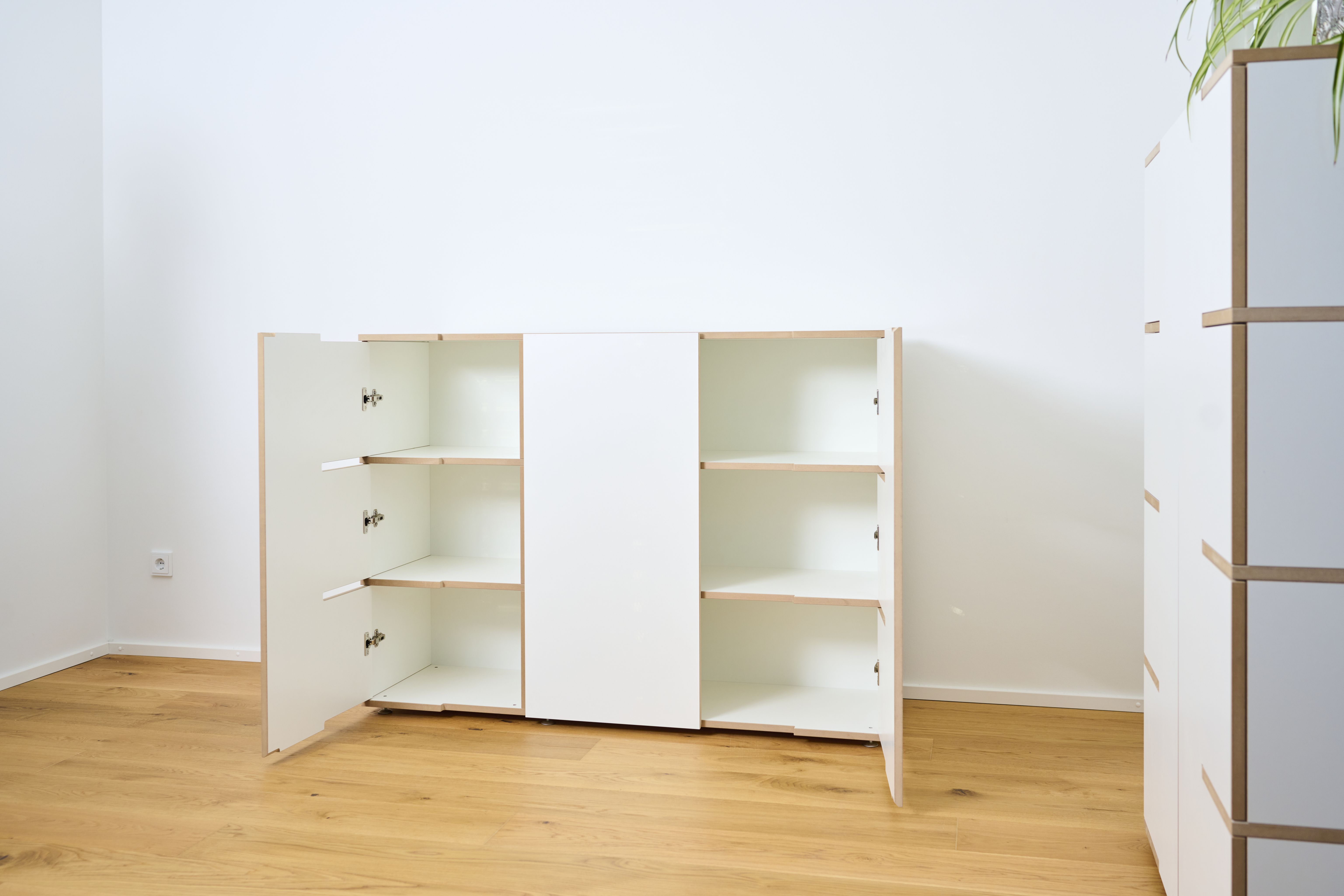 Stau Sideboard Tojo aus weißem Holz mit offenen Türen und Einlegeböden auf Holzboden.