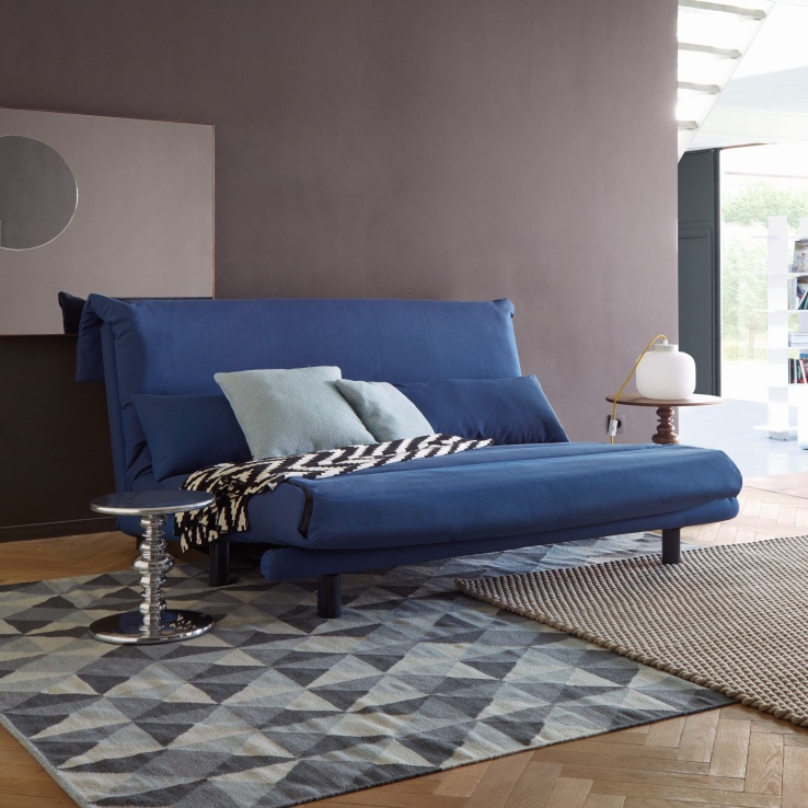 Blaues Multy Schlafsofa von ligne roset mit Kissen und Decke im modernen Wohnzimmer.