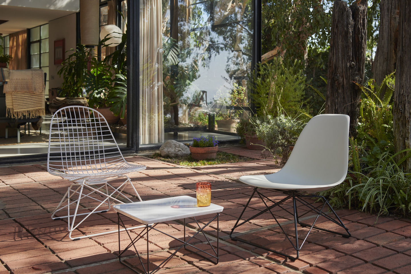 Eames Fiberglass Chair von Vitra mit Sitzpolster, grauer Stuhl mit schwarzem Metallgestell im Garten.