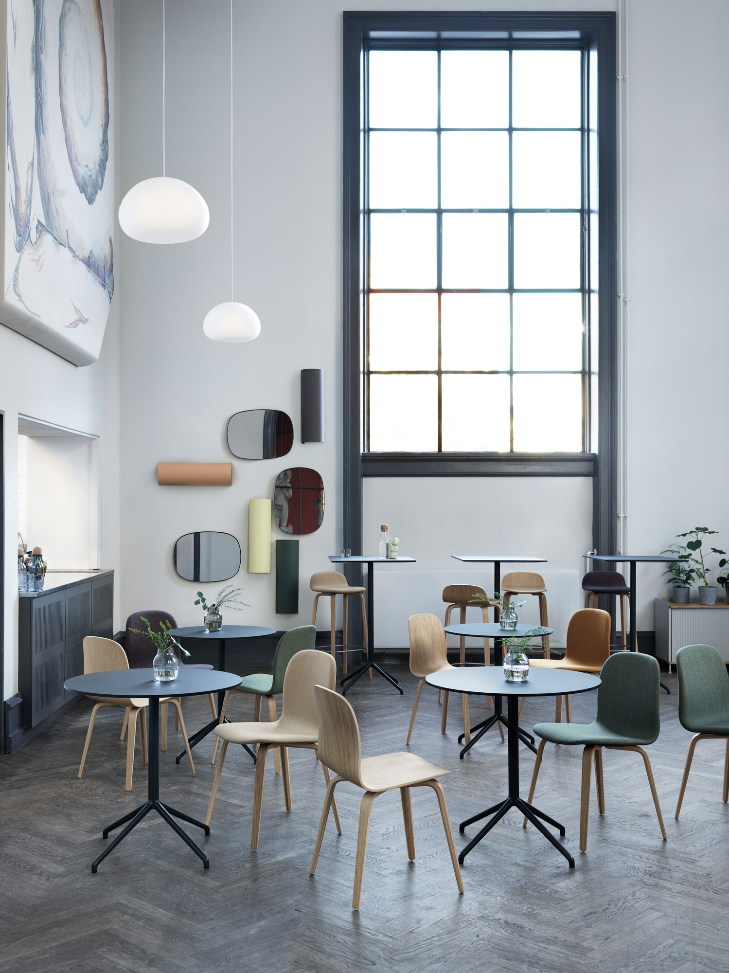 Innenraumansicht mit mehreren Visu Chair Wood Base Stühlen von Muuto in verschiedenen Farben und Holztönen.