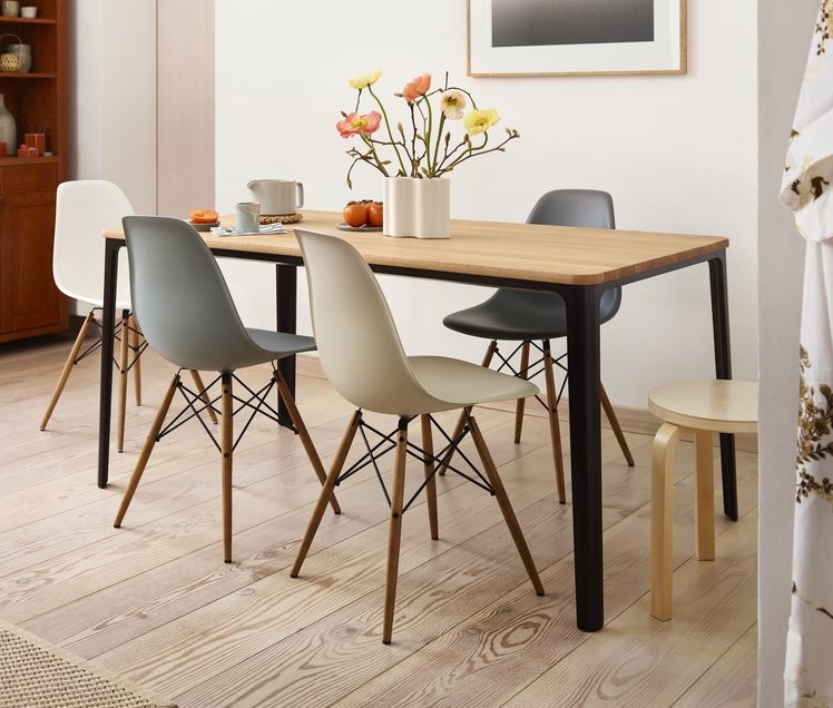 Esstisch aus Holz mit schwarzen Beinen und bunten Design Stühlen im Esszimmer.